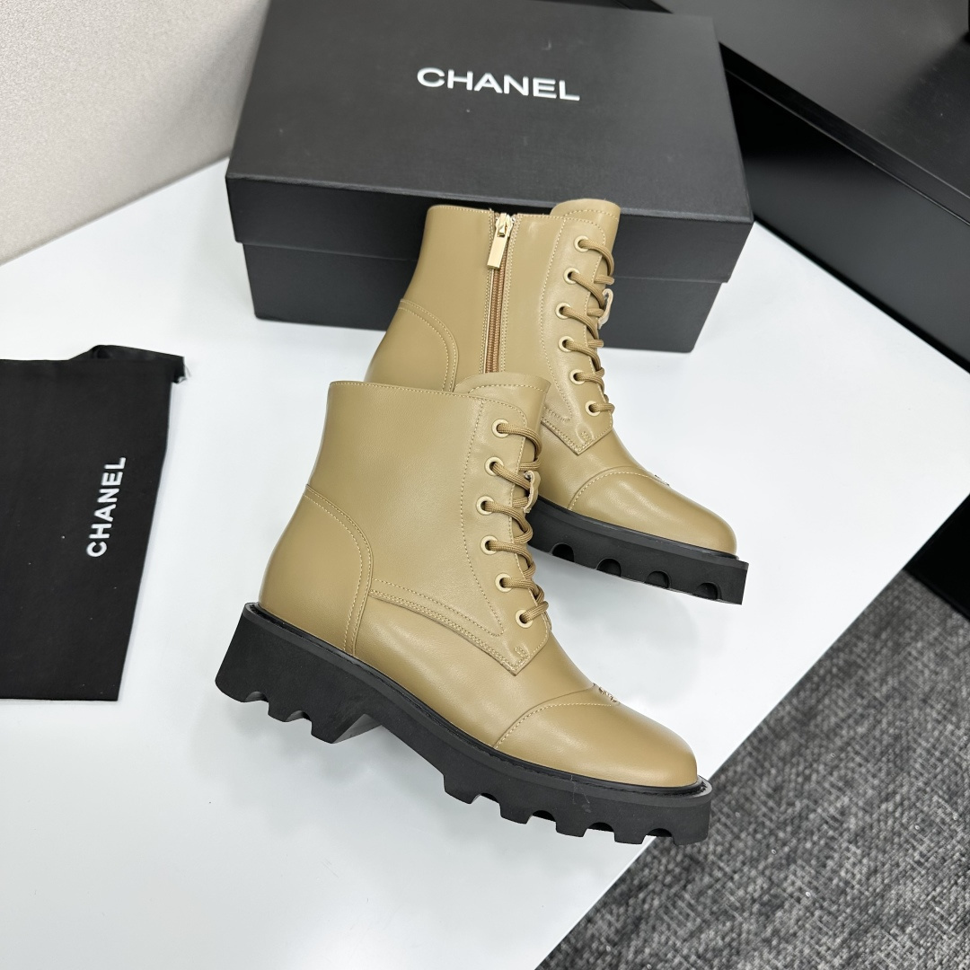 Pair of beige designer leather combat boots with chunky black soles and side zippers displayed on a black box. - Hình 7
