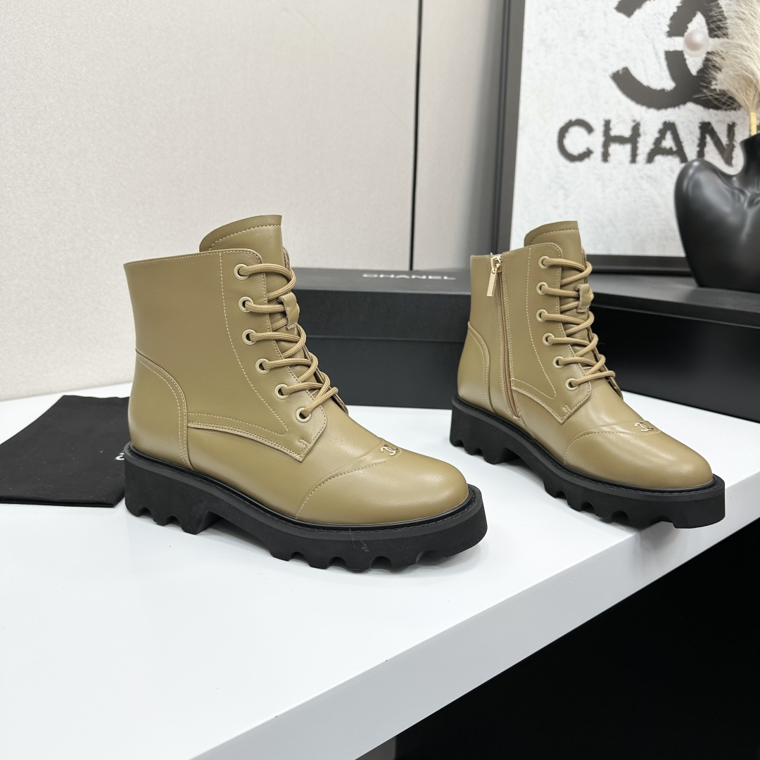Pair of beige designer leather combat boots with chunky black soles and side zippers displayed on a black box. - Hình 6
