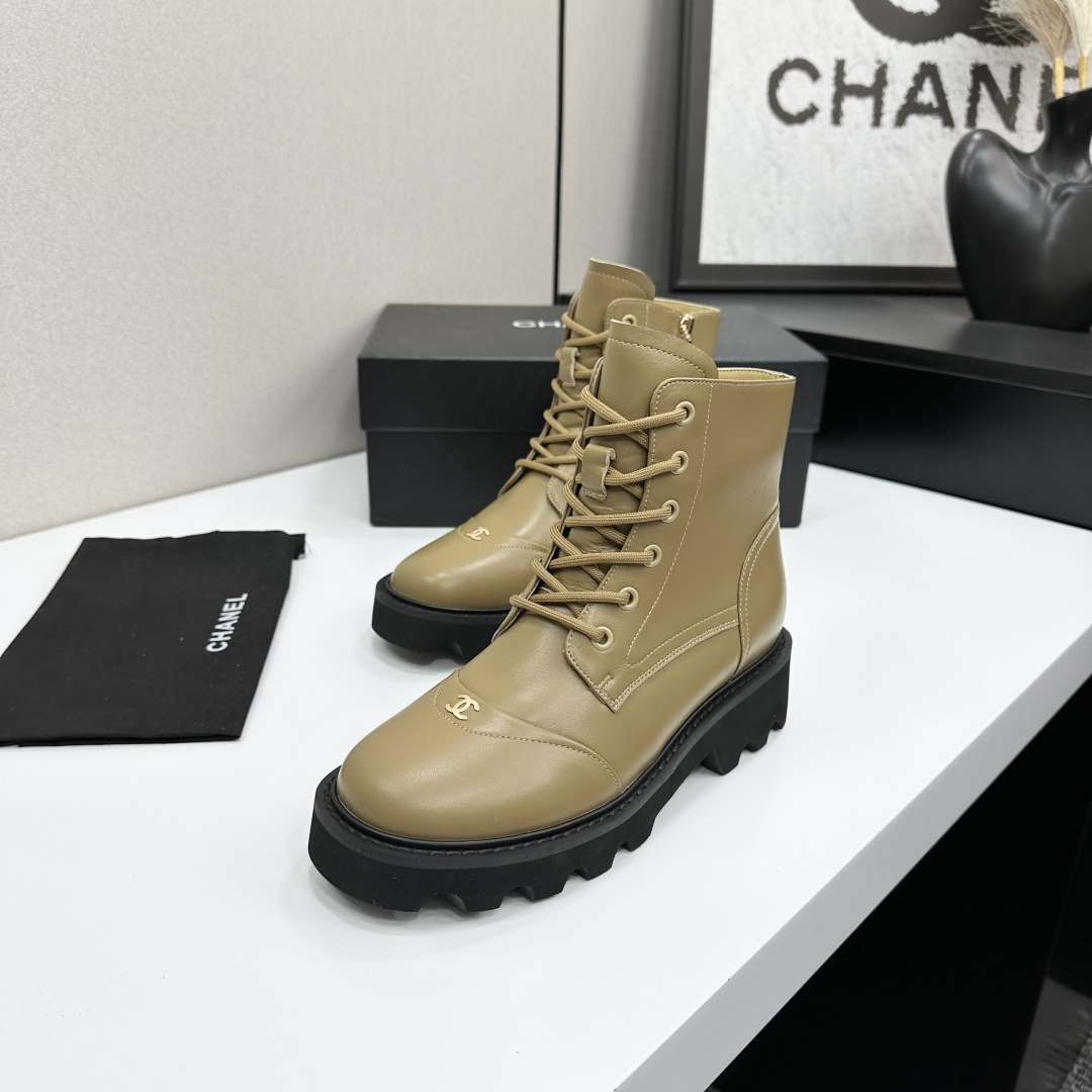 Pair of beige designer leather combat boots with chunky black soles and side zippers displayed on a black box. - Hình 4