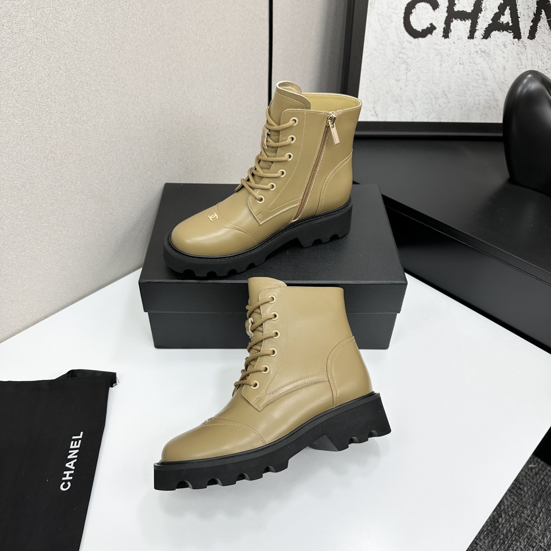 Pair of beige designer leather combat boots with chunky black soles and side zippers displayed on a black box. - Hình 3