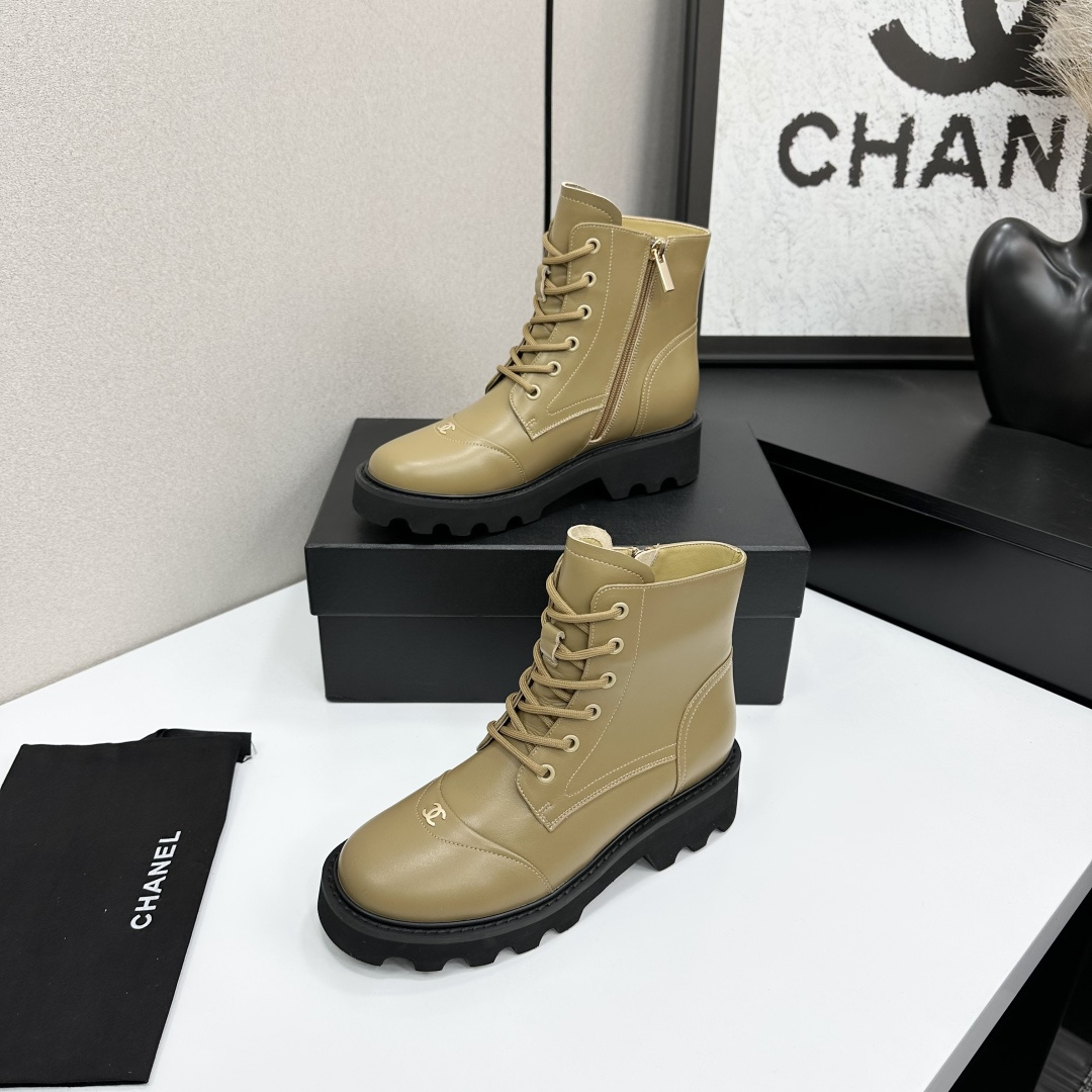 Pair of beige designer leather combat boots with chunky black soles and side zippers displayed on a black box. - Hình 2