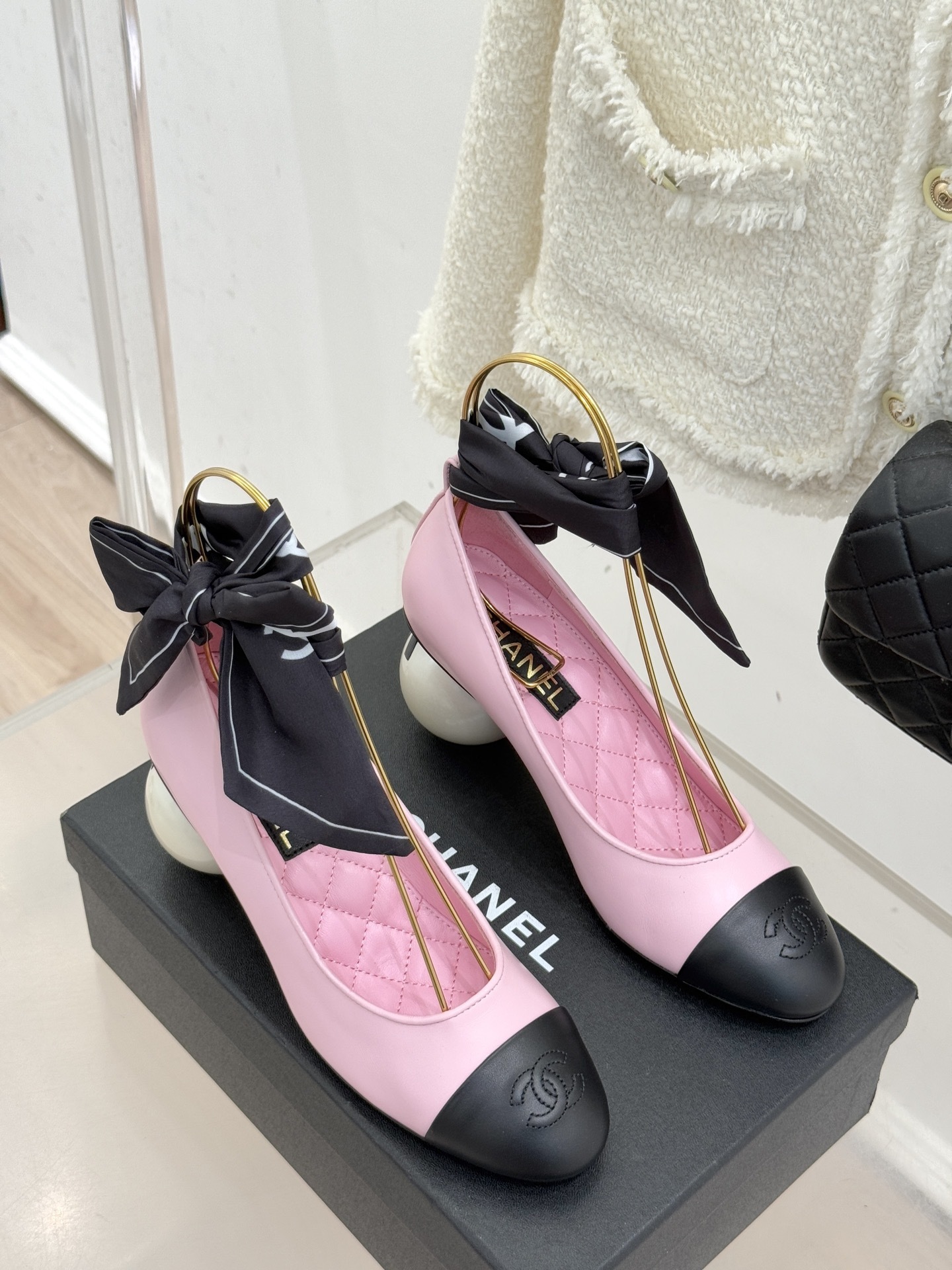 Chanel pink leather pumps with black cap toe and a large white pearl heel, featuring black bow accents on top. - Hình 3