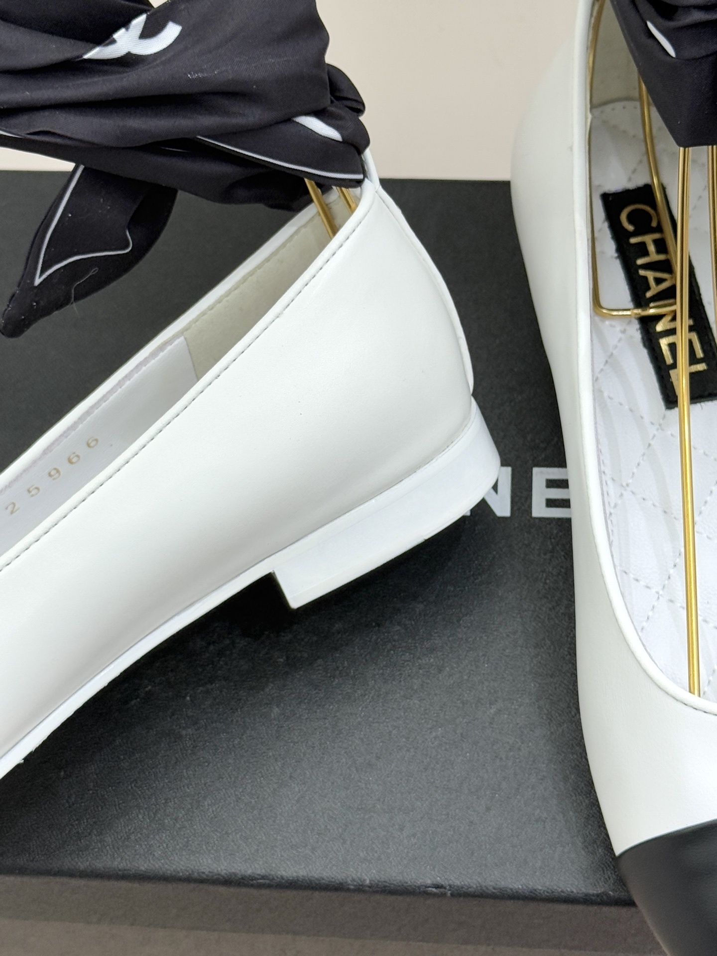 Pair of Chanel white leather ballerina flats with black cap-toe and black silk ribbon ankle ties on a black box - Hình 6