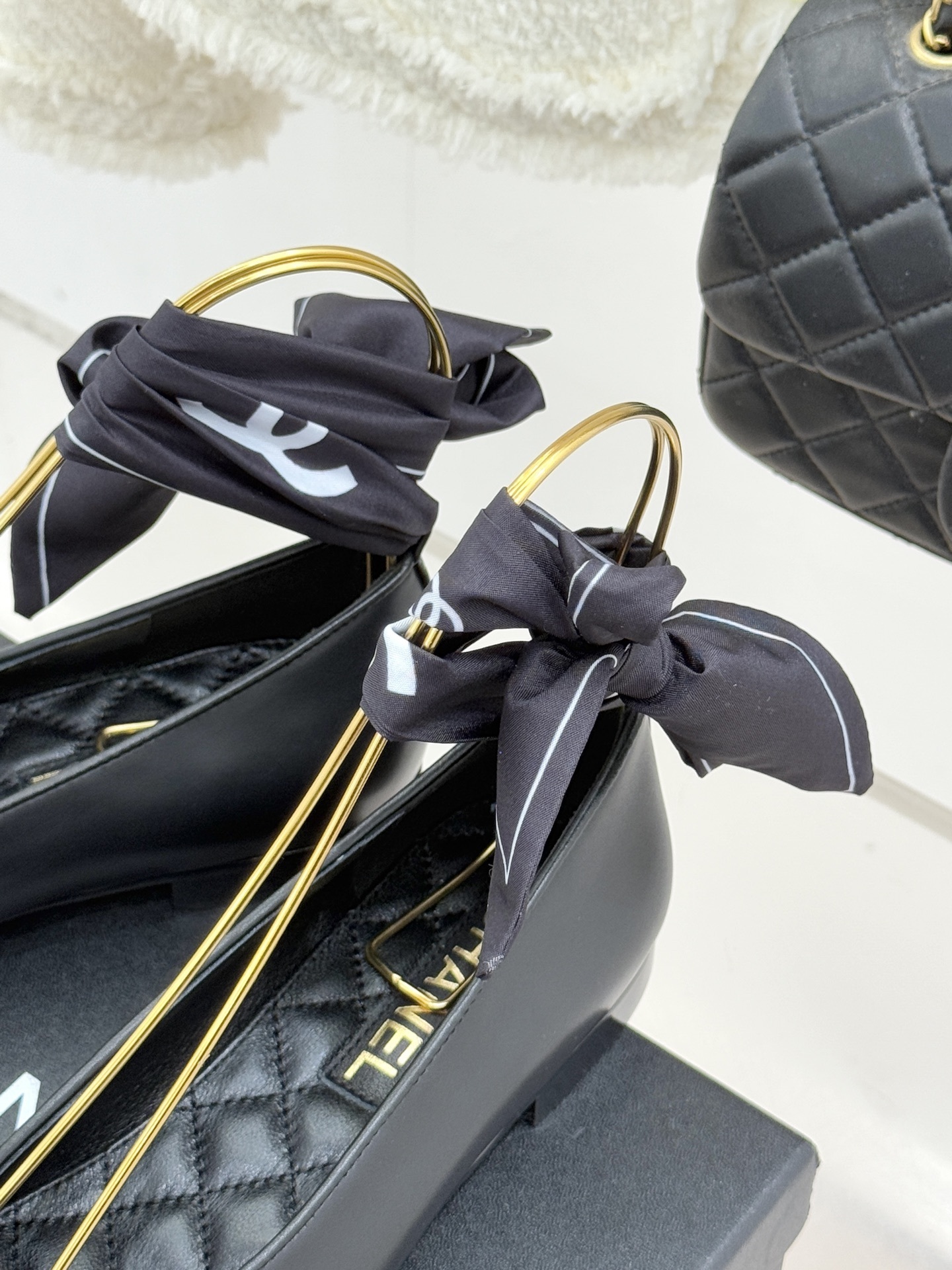 Luxury Chanel black leather ballerina flats with embossed CC logo and a black and white silk scarf ankle wrap displayed on a Chanel box. - Hình 8