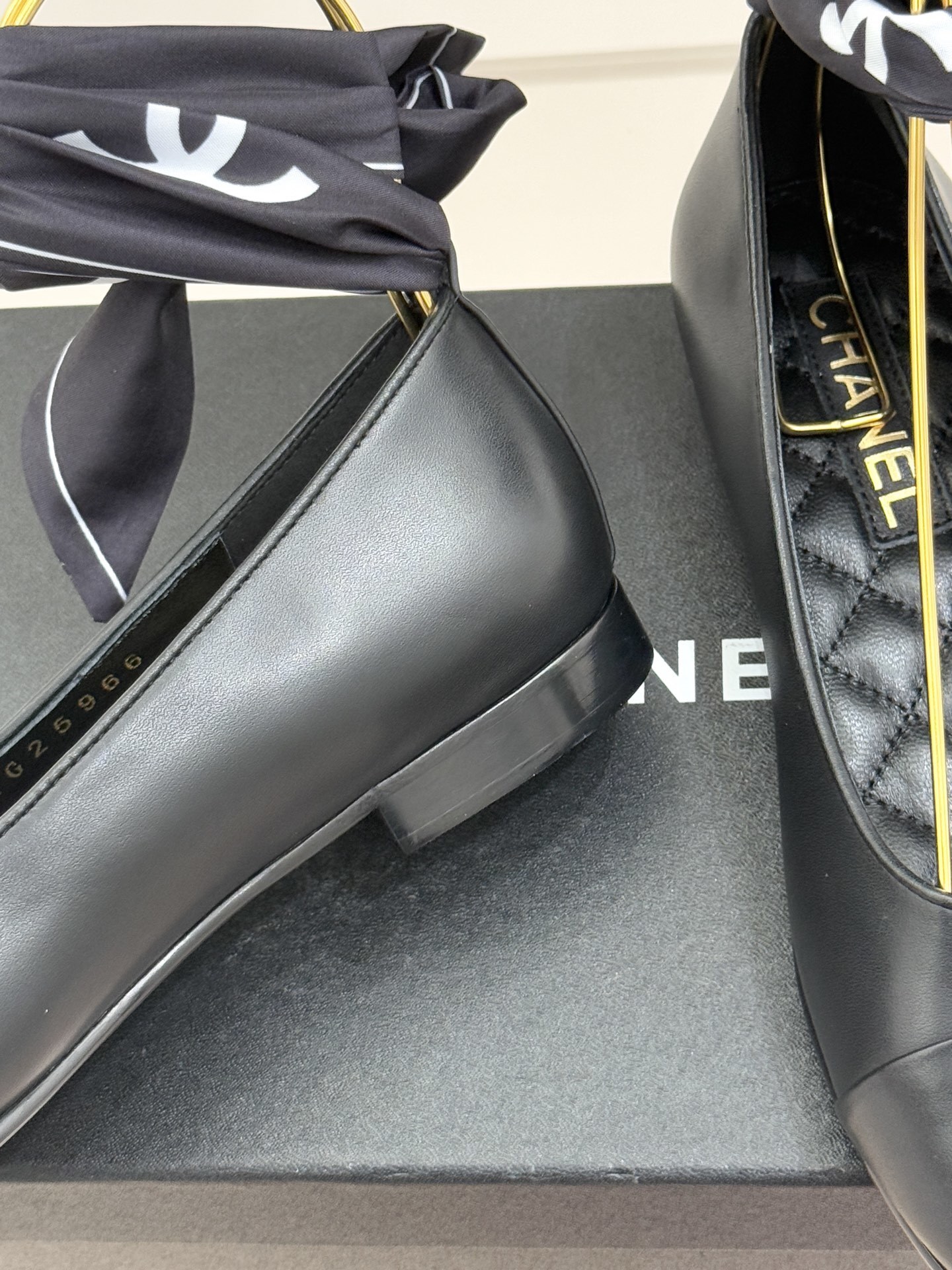 Luxury Chanel black leather ballerina flats with embossed CC logo and a black and white silk scarf ankle wrap displayed on a Chanel box. - Hình 6