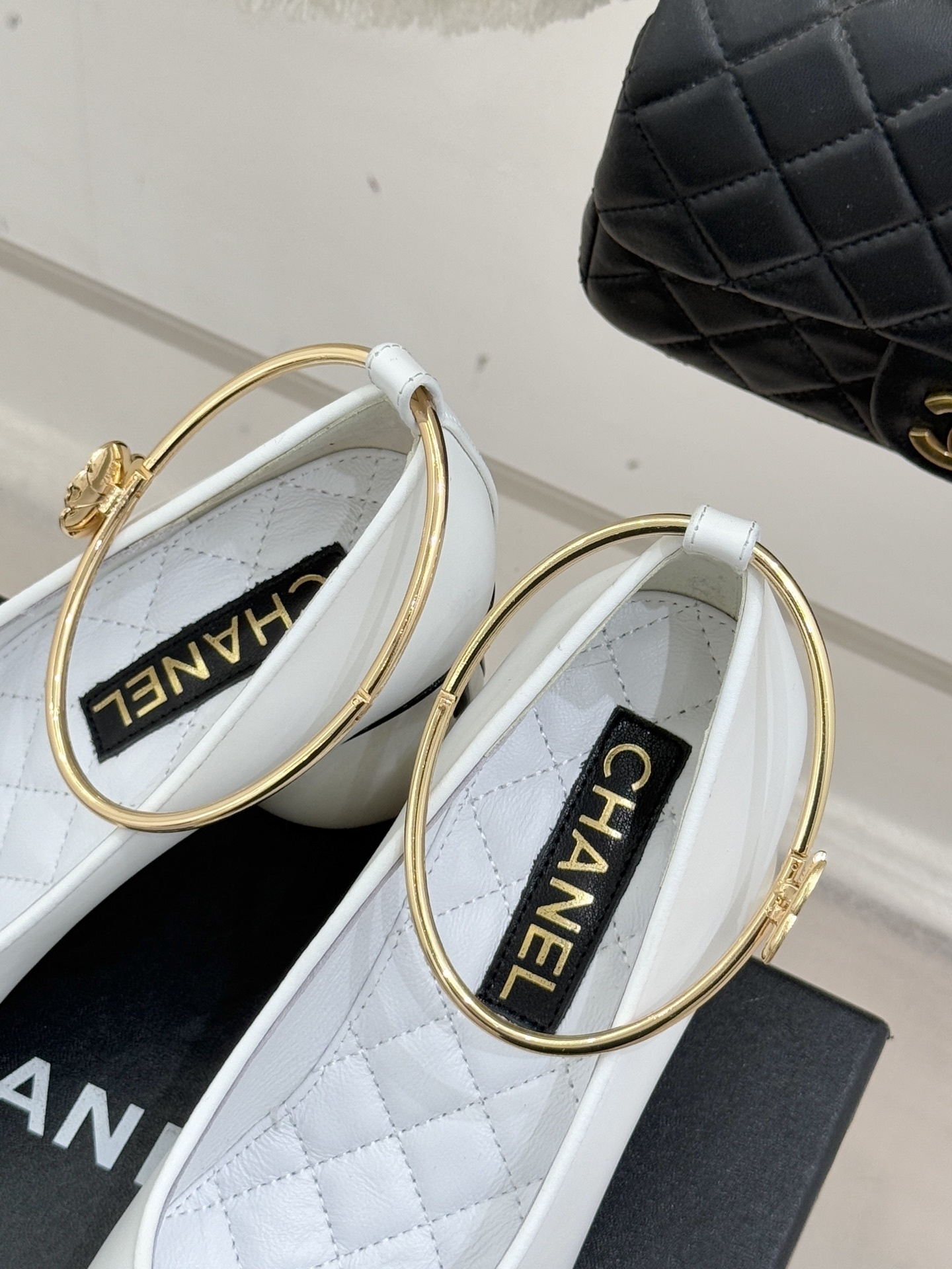 Pair of Chanel white and black bicolor pumps with a spherical pearl heel and gold-tone ankle rings displayed on a black box. - Hình 8