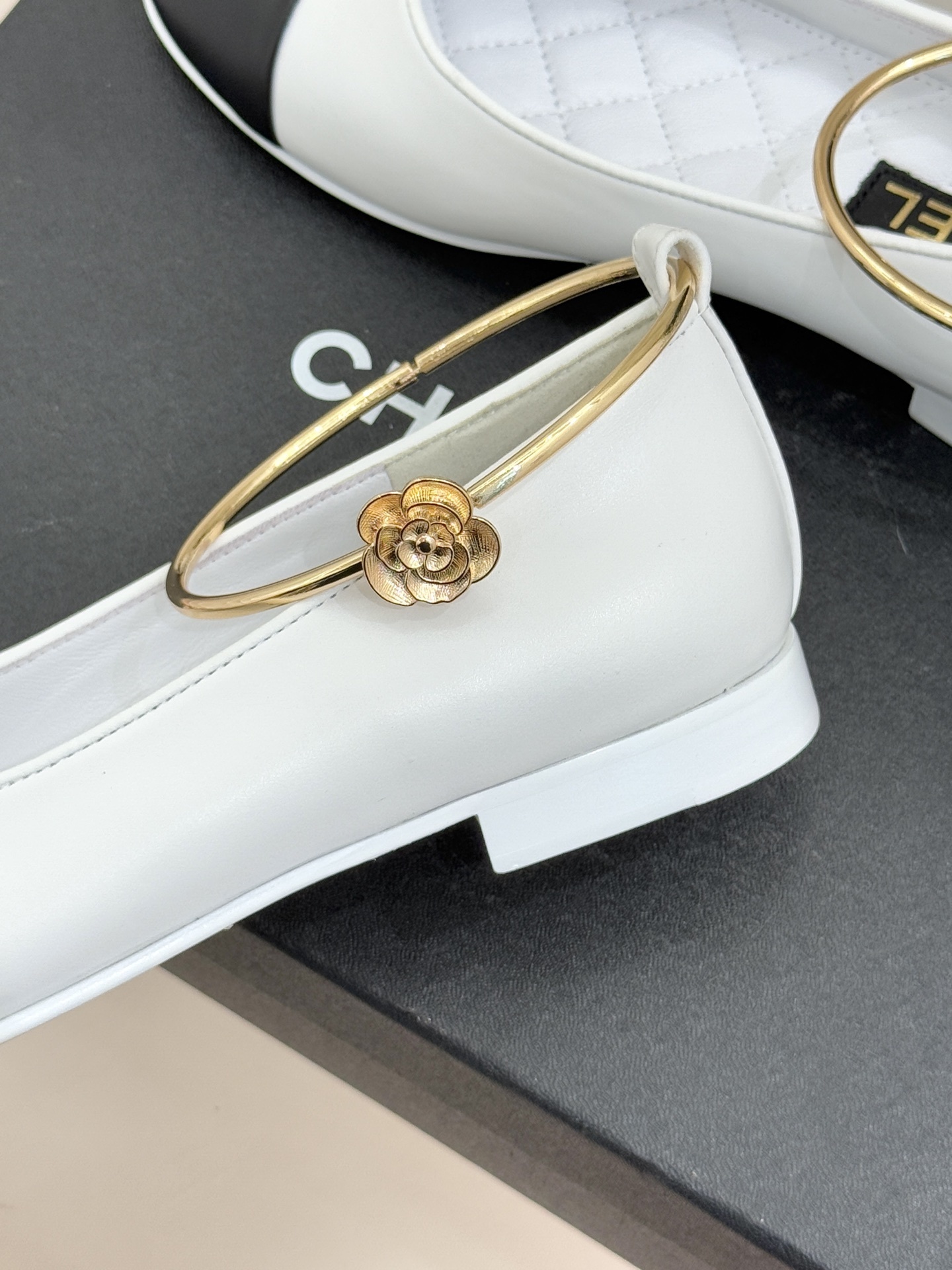 Luxury Chanel white leather ballet flats with black toe cap and gold-tone metal ankle ring detail. - Hình 6