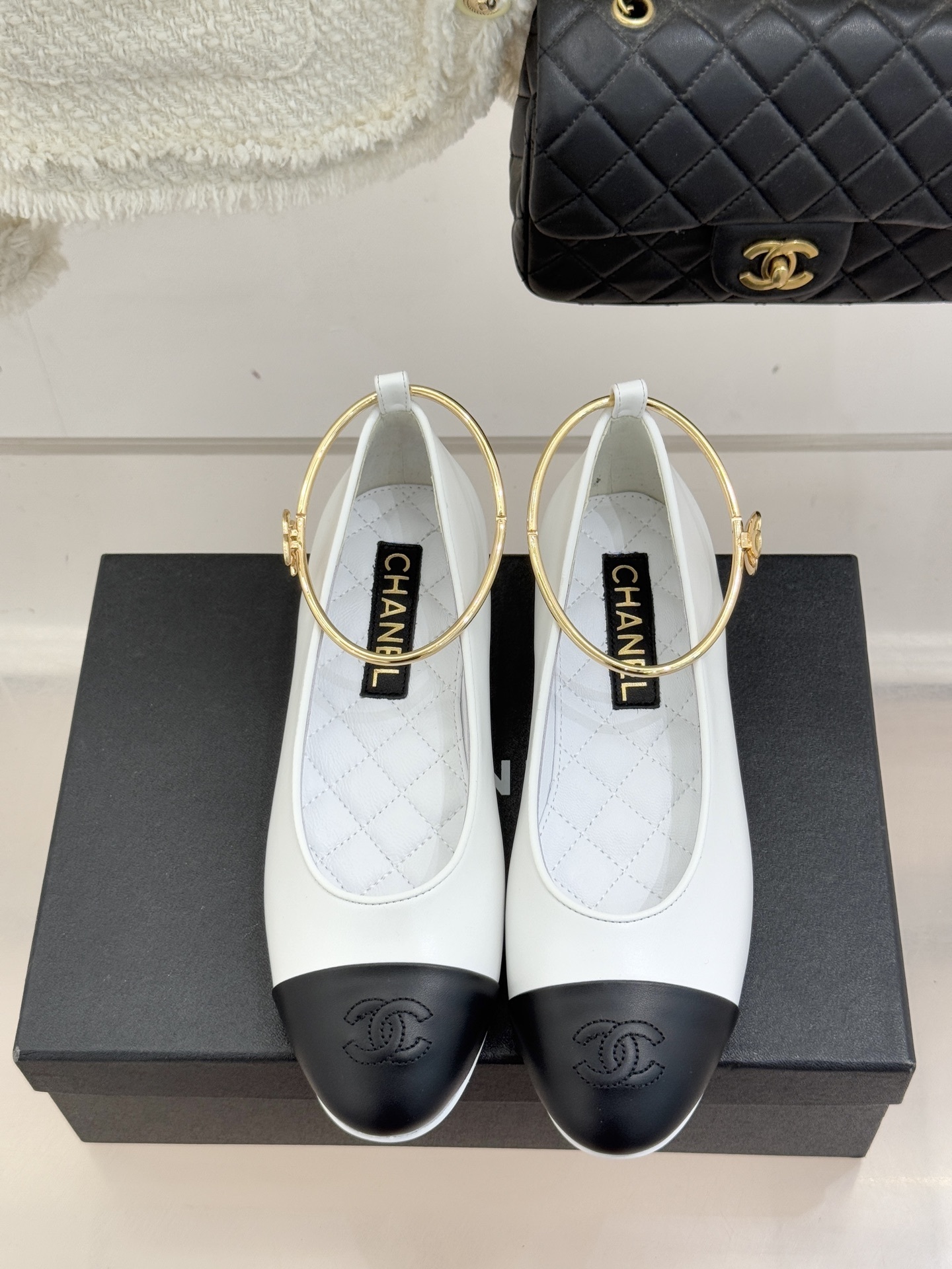 Luxury Chanel white leather ballet flats with black toe cap and gold-tone metal ankle ring detail. - Hình 4