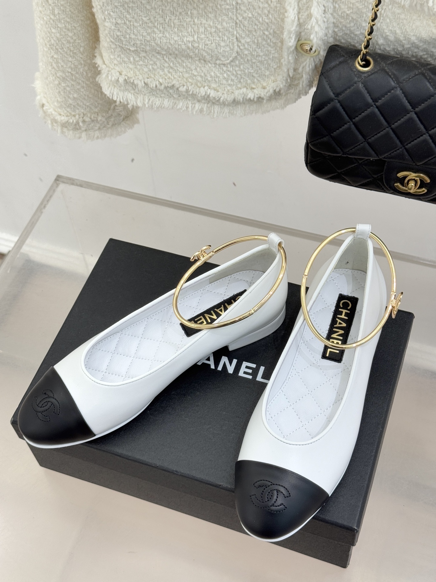 Luxury Chanel white leather ballet flats with black toe cap and gold-tone metal ankle ring detail. - Hình 2