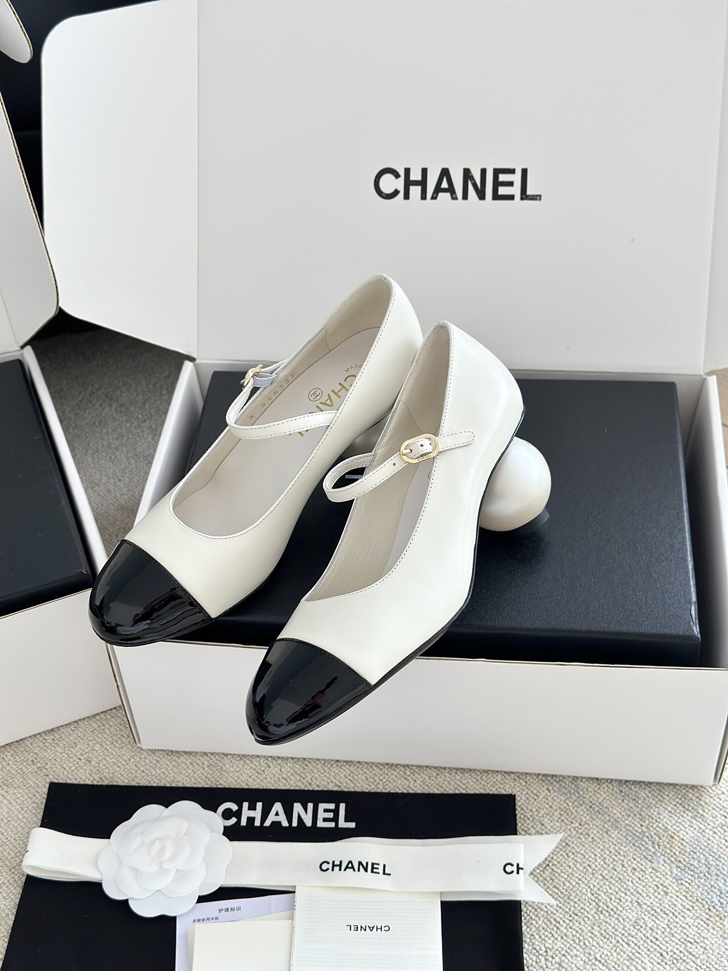 Luxury Chanel Mary Jane pumps in white leather with black patent leather cap toe and block heel, presented in a signature white box. - Hình 4