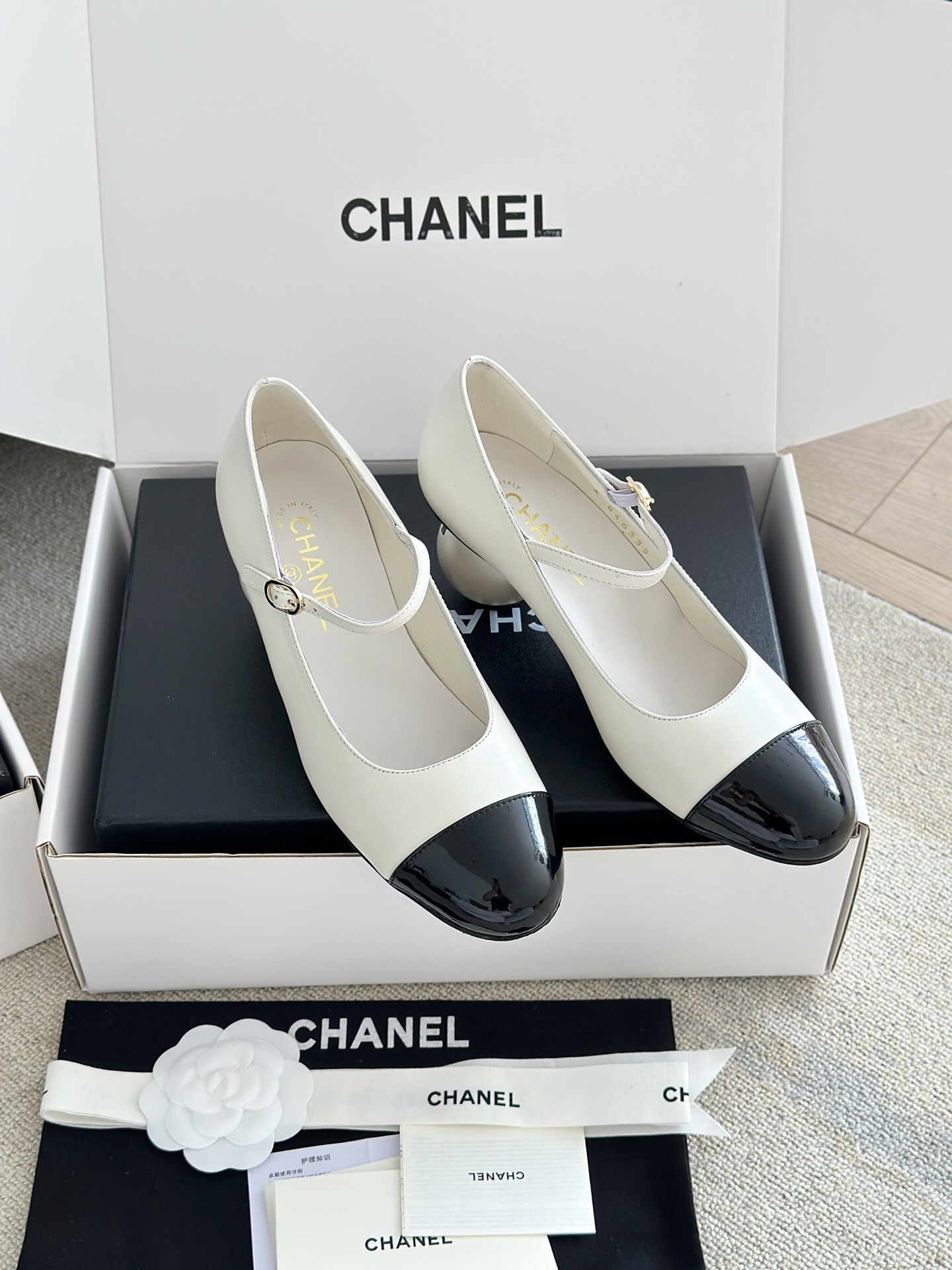 Luxury Chanel Mary Jane pumps in white leather with black patent leather cap toe and block heel, presented in a signature white box. - Hình 3