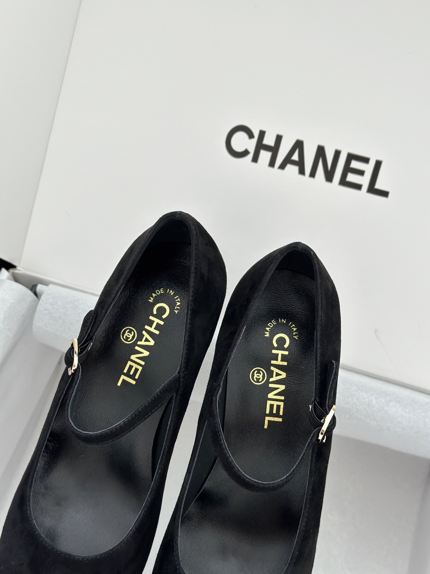 A pair of black Chanel suede Mary Jane pumps with patent leather cap toes and a distinctive white pearl heel displayed in a luxury white box. - Hình 7