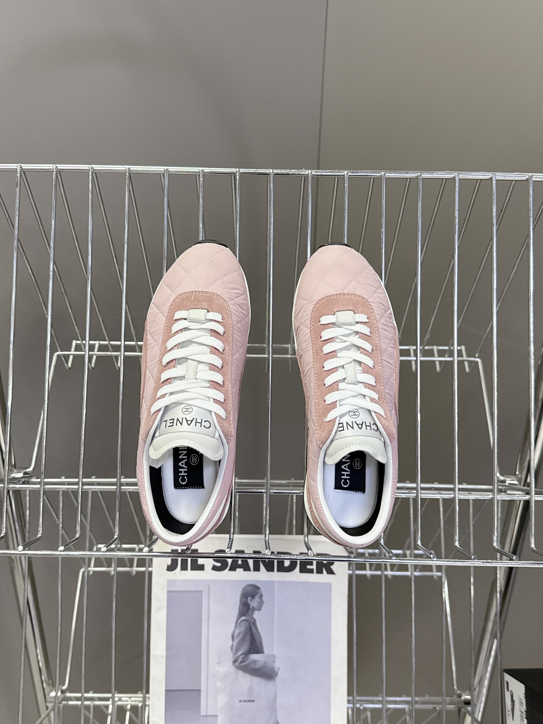 A pair of luxury Chanel pink quilted sneakers with suede trim and white laces placed next to a Chanel branded shoe box. - Hình 6
