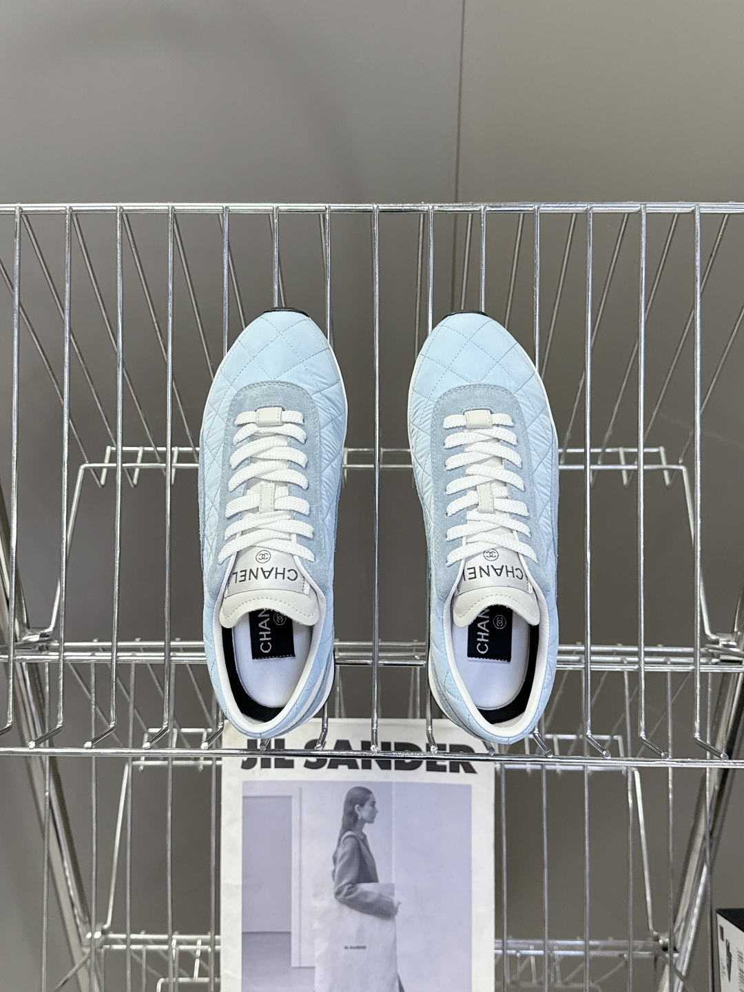 A pair of light blue quilted Chanel sneakers with suede details and white laces next to a black Chanel box - Hình 6