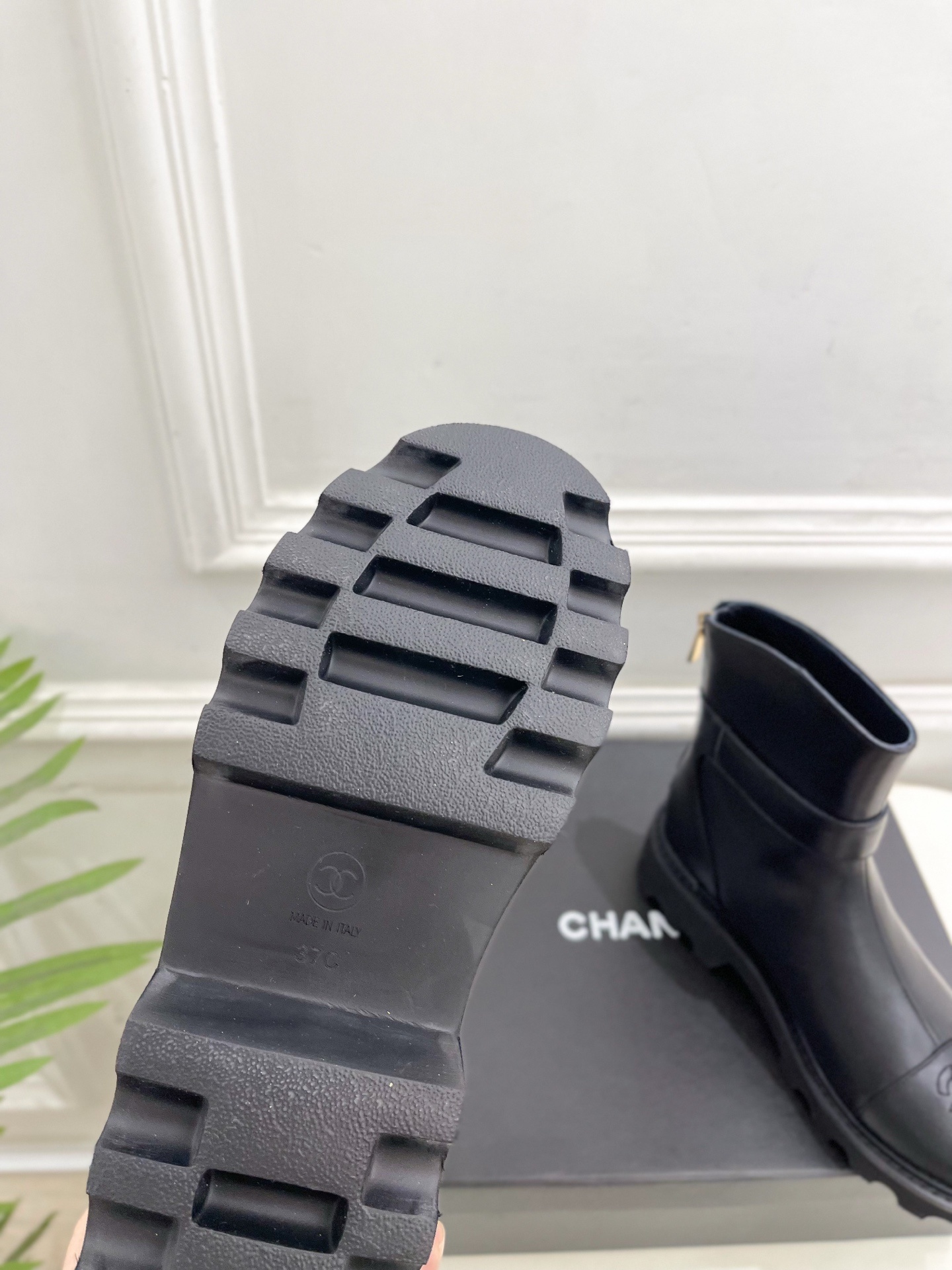 Pair of Chanel black leather ankle boots with gold CC logo and chunky platform sole on a black box. - Hình 9