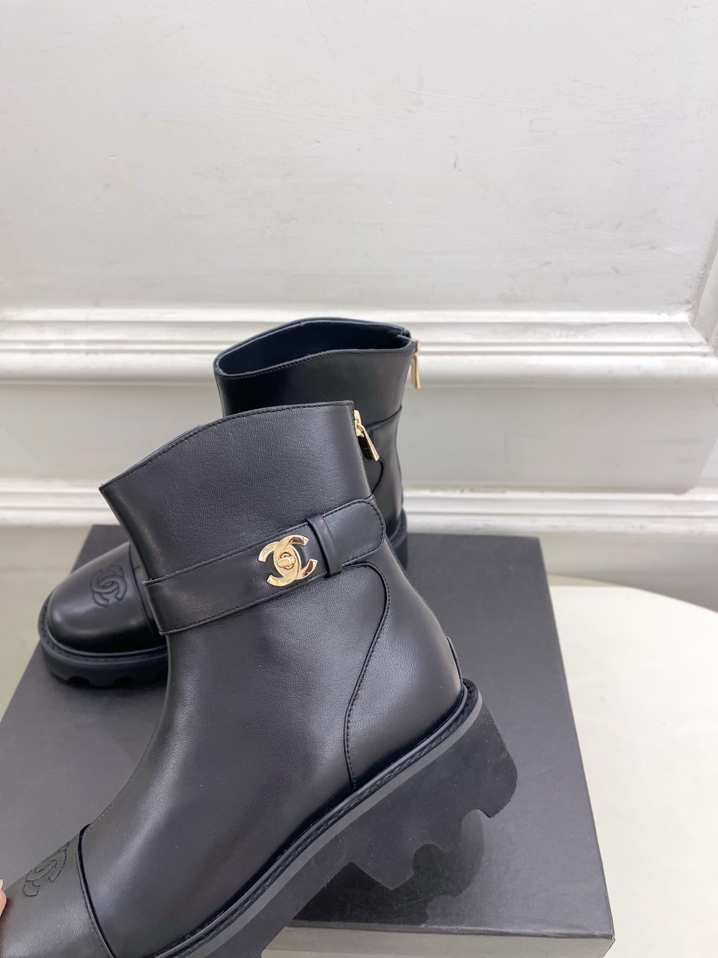 Pair of Chanel black leather ankle boots with gold CC logo and chunky platform sole on a black box. - Hình 8