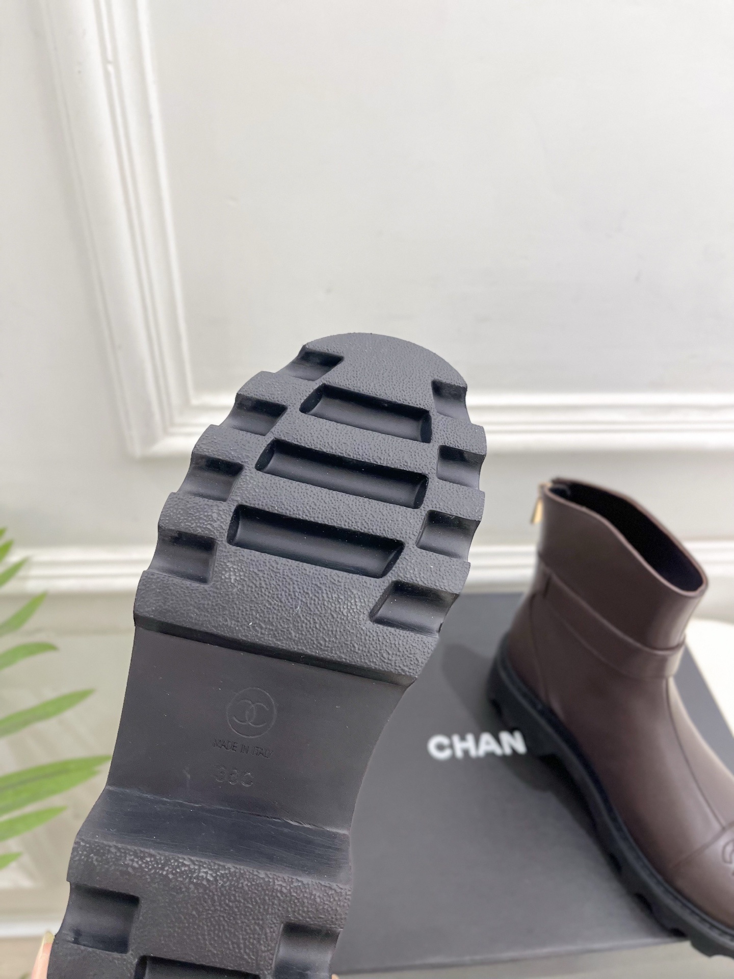 Pair of Chanel dark brown leather ankle boots with CC logo on toe and gold buckle strap on a black box - Hình 9