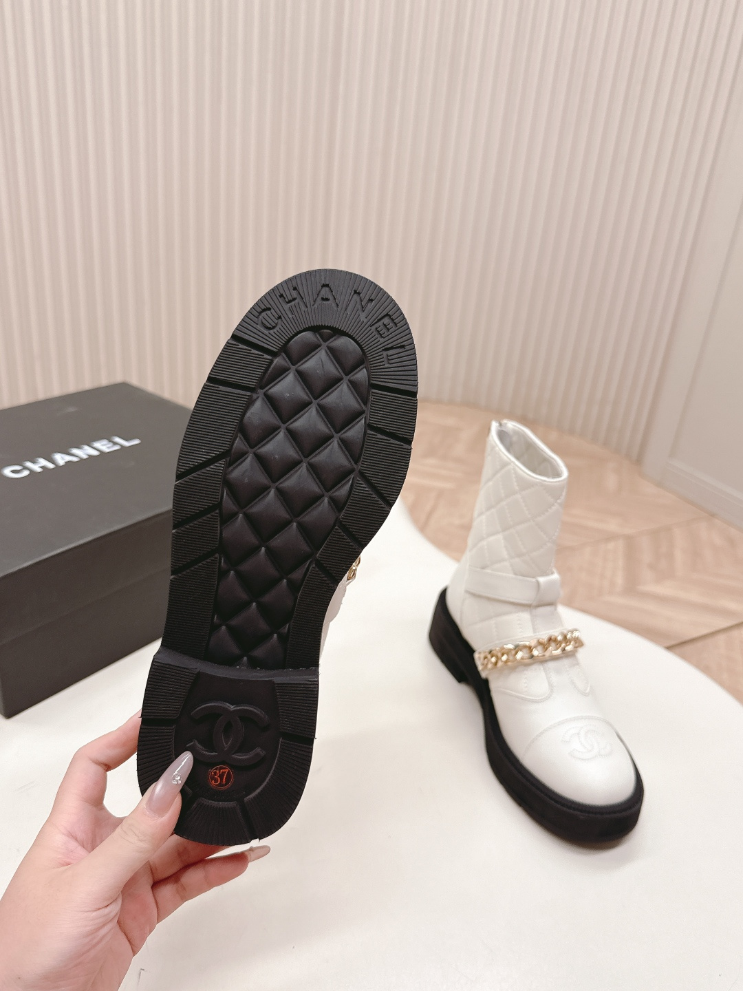 Luxury white quilted ankle boots with gold chain accents and a chunky black platform sole shown next to a designer box - Hình 8