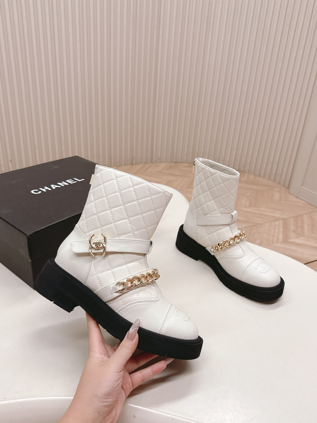 Luxury white quilted ankle boots with gold chain accents and a chunky black platform sole shown next to a designer box - Hình 7