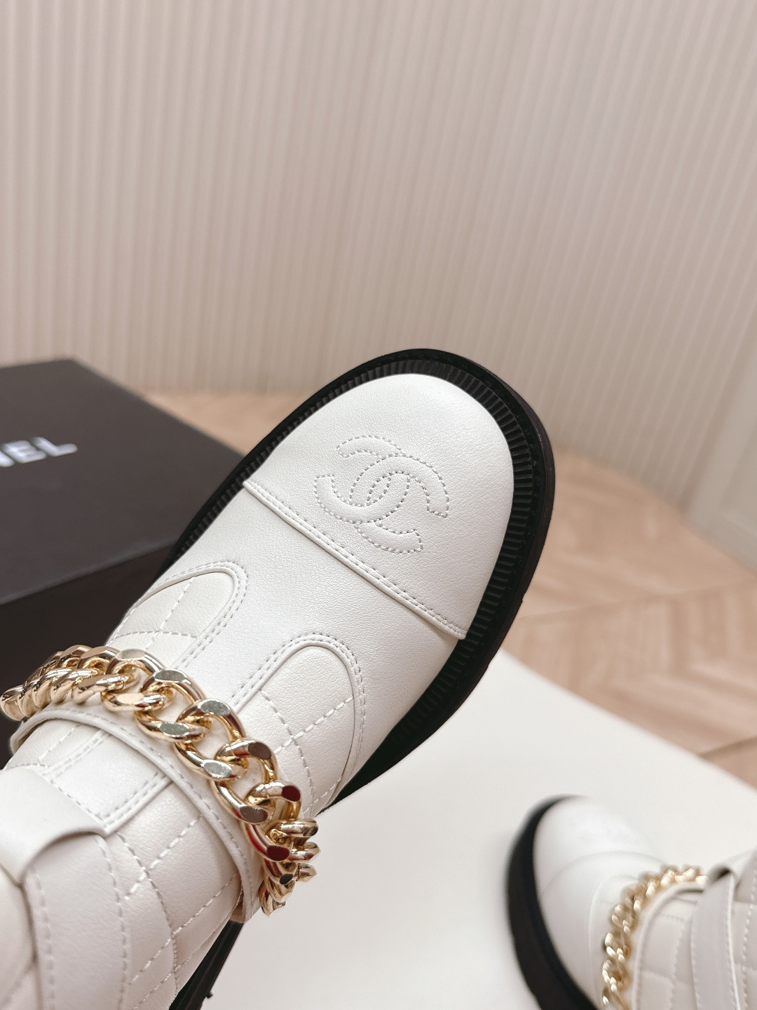 Luxury white quilted ankle boots with gold chain accents and a chunky black platform sole shown next to a designer box - Hình 6