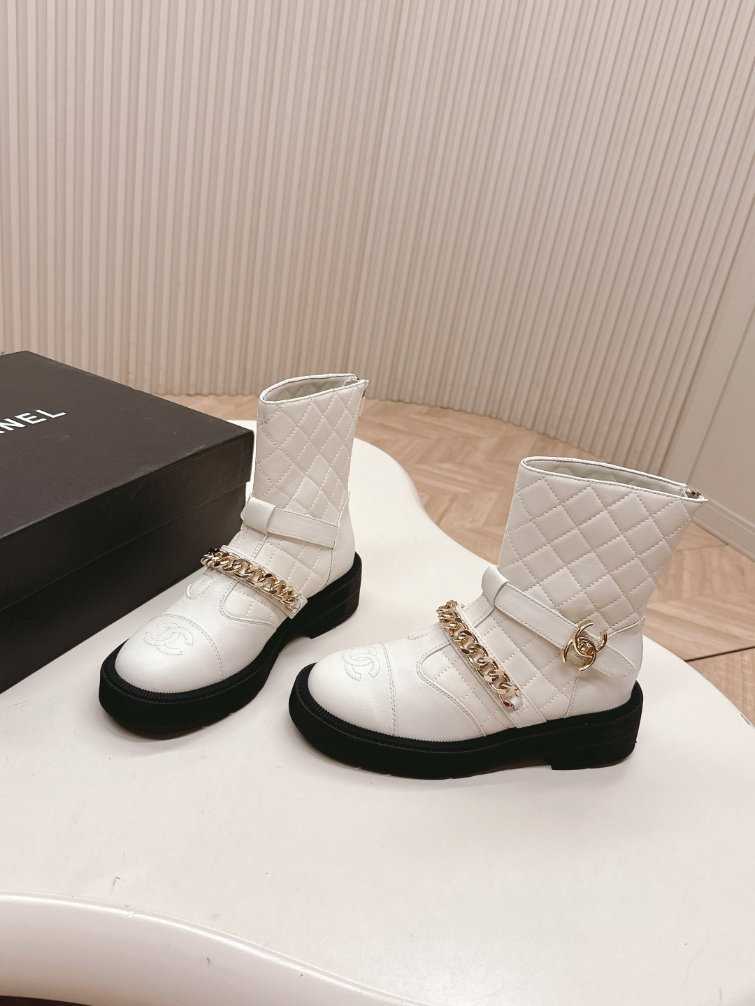 Luxury white quilted ankle boots with gold chain accents and a chunky black platform sole shown next to a designer box - Hình 3