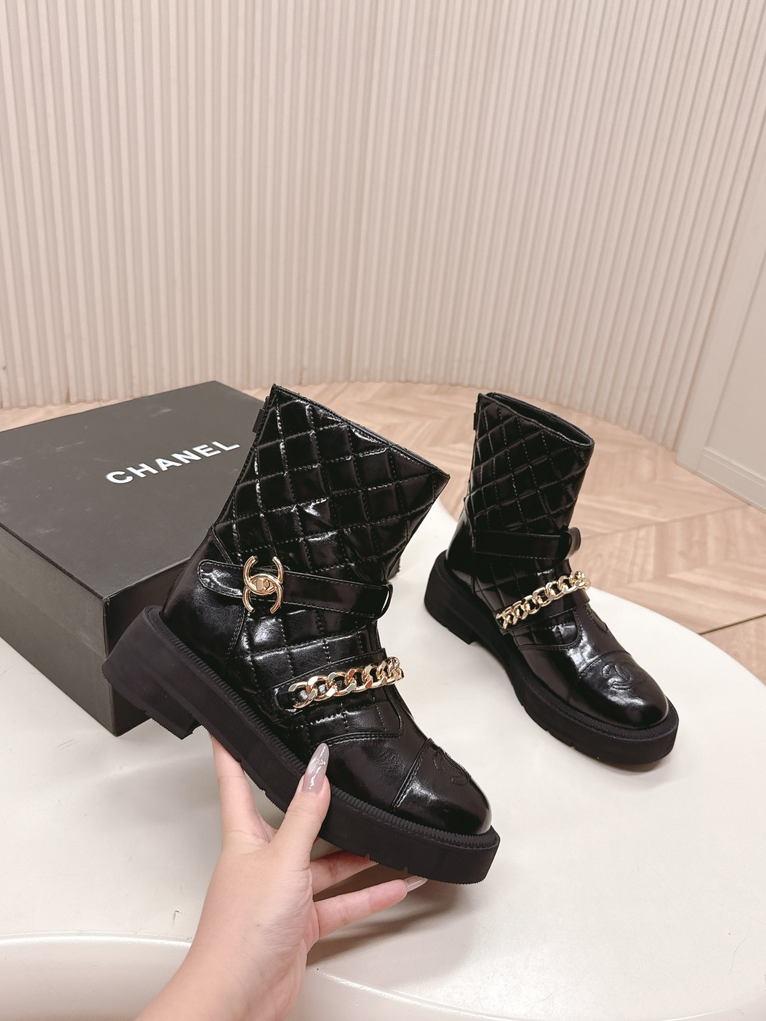 Black quilted leather ankle boots with gold chain strap and chunky rubber soles on a white surface. - Hình 8