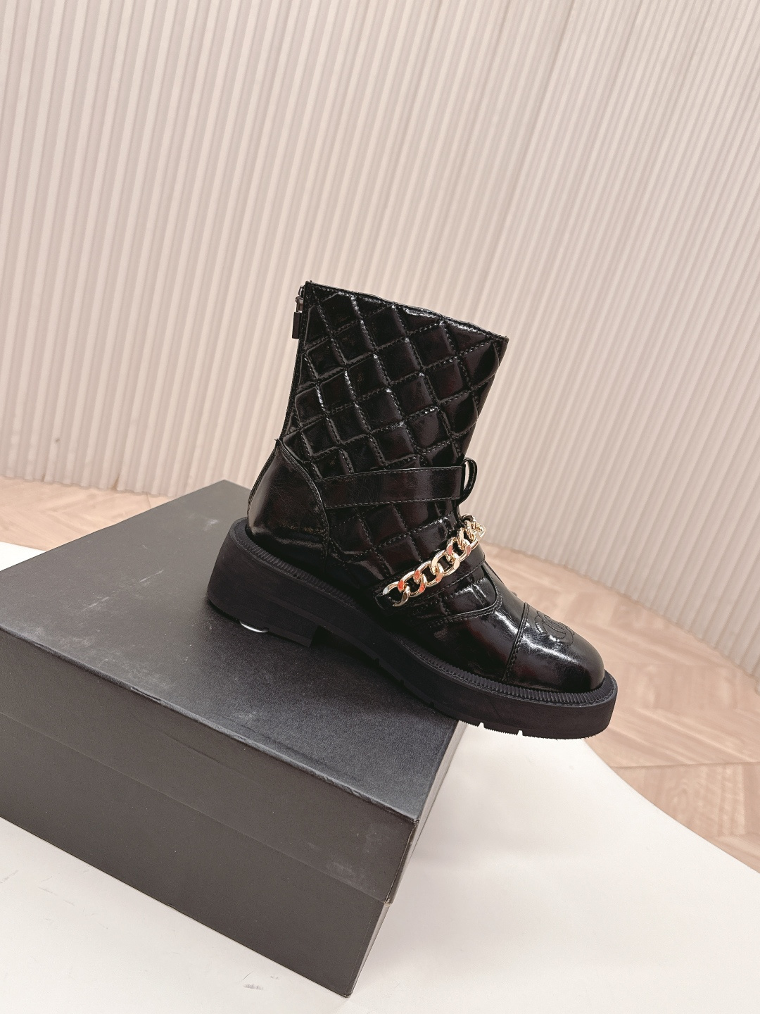 Black quilted leather ankle boots with gold chain strap and chunky rubber soles on a white surface. - Hình 3