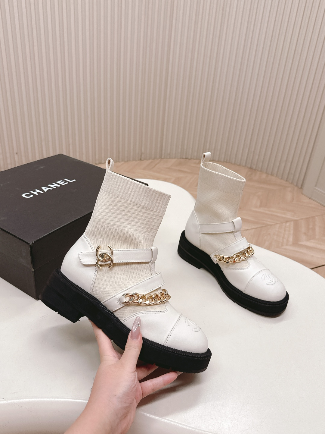 Pair of Chanel white leather sock ankle boots with gold chain and CC logo on a white table - Hình 6