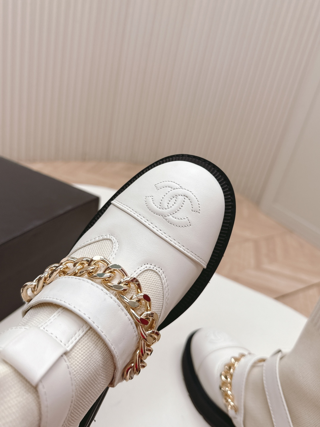 Pair of Chanel white leather sock ankle boots with gold chain and CC logo on a white table - Hình 5