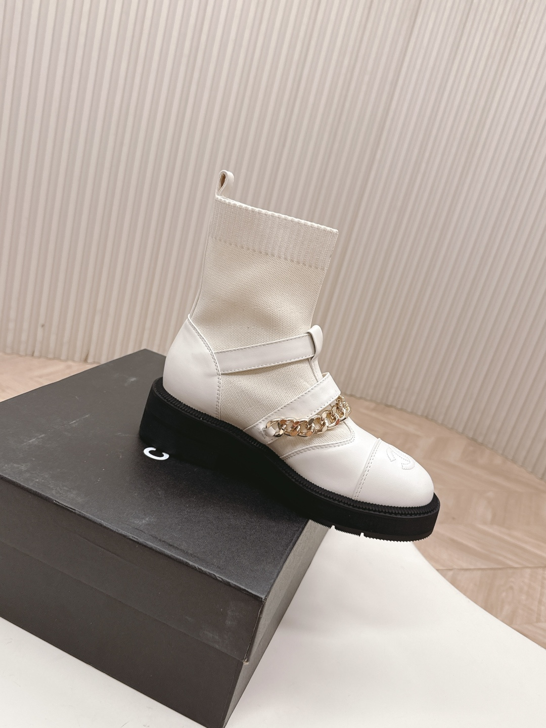 Pair of Chanel white leather sock ankle boots with gold chain and CC logo on a white table - Hình 4
