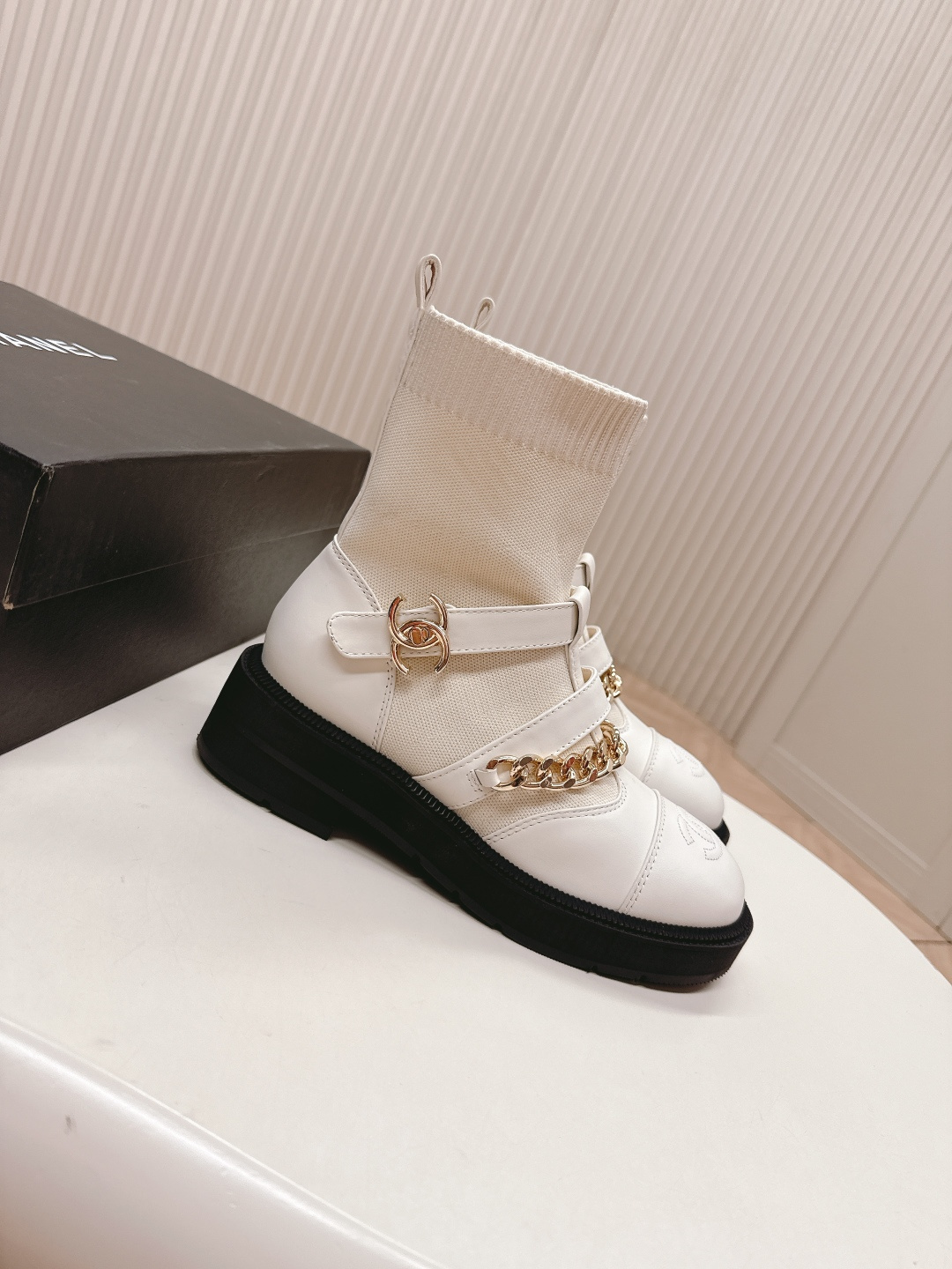 Pair of Chanel white leather sock ankle boots with gold chain and CC logo on a white table - Hình 3