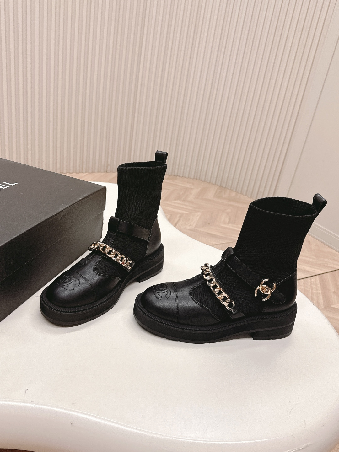 A pair of stylish black sock boots featuring gold chain hardware and chunky soles displayed on a white surface. - Hình 8