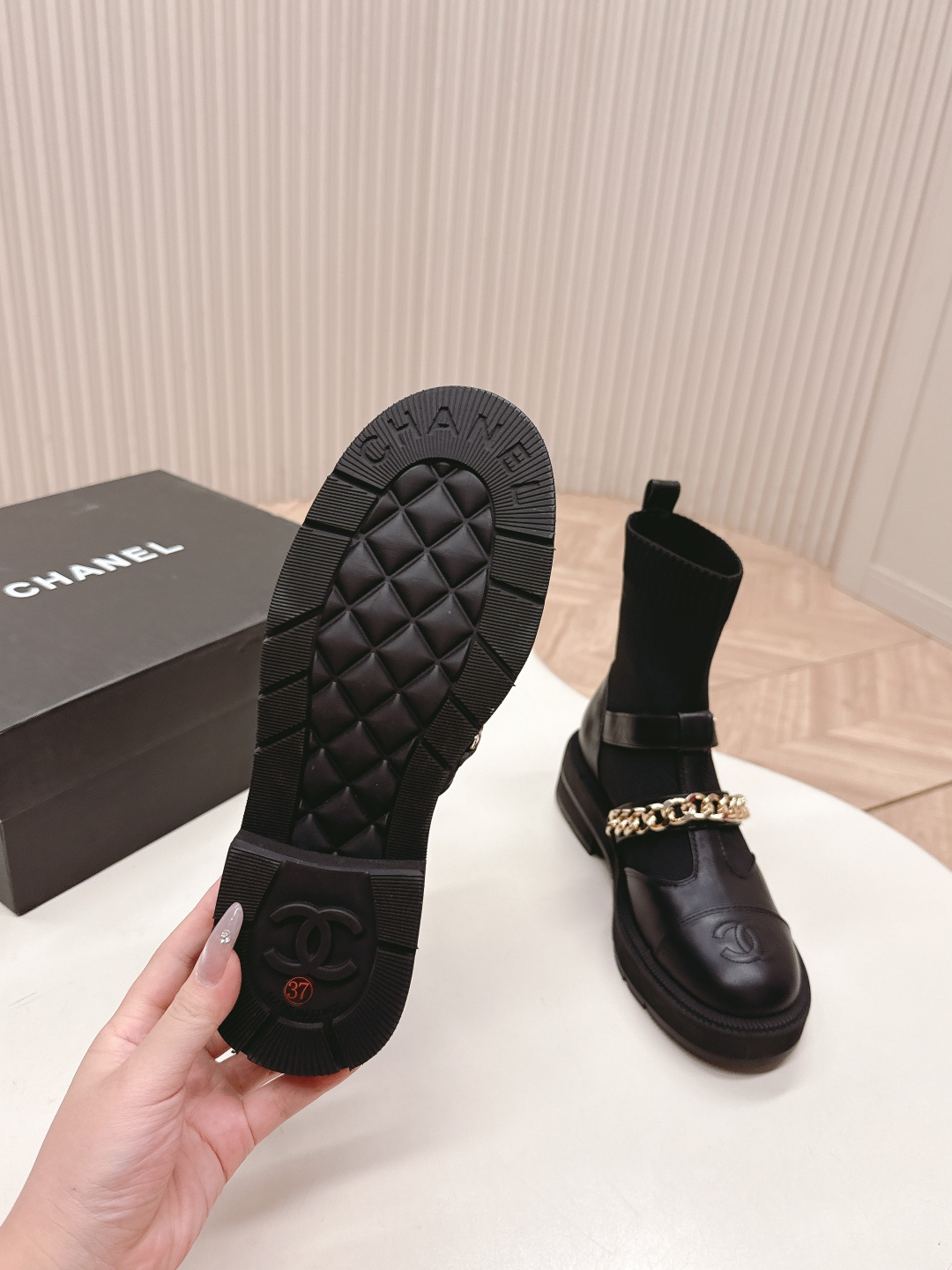A pair of stylish black sock boots featuring gold chain hardware and chunky soles displayed on a white surface. - Hình 7