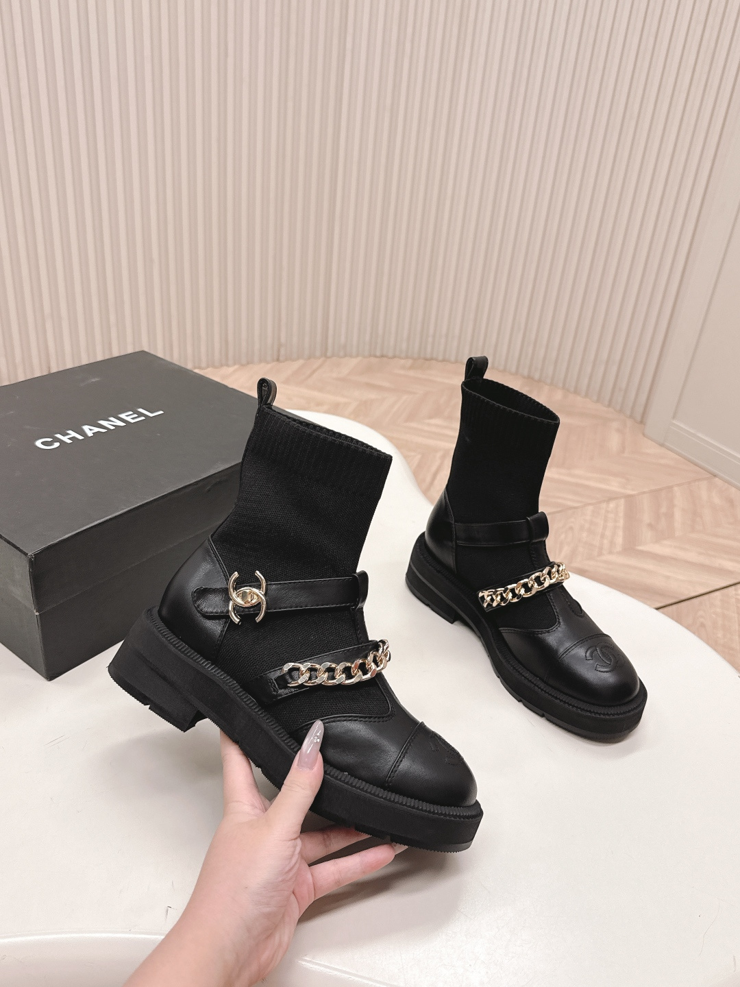 A pair of stylish black sock boots featuring gold chain hardware and chunky soles displayed on a white surface. - Hình 6