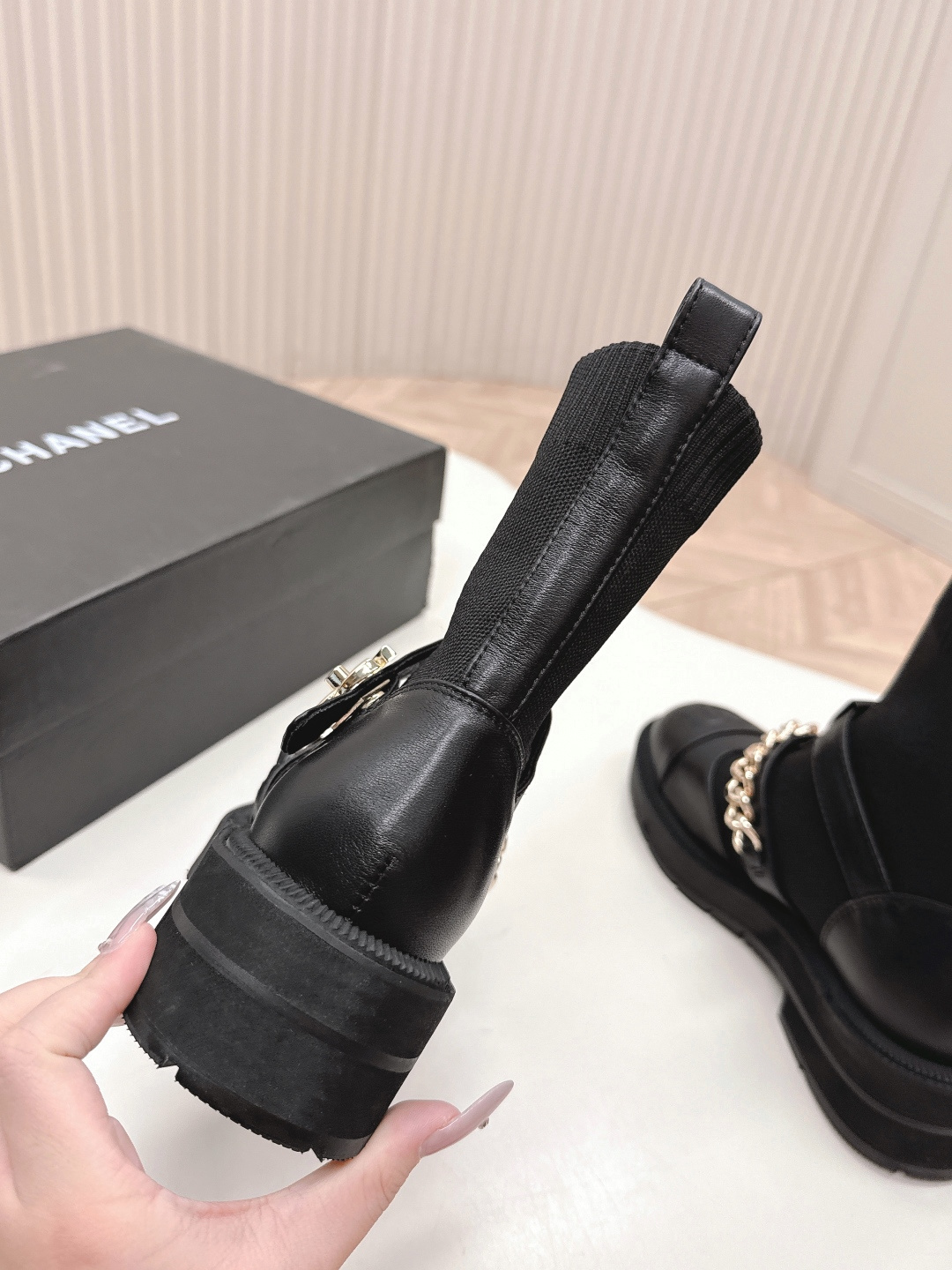 A pair of stylish black sock boots featuring gold chain hardware and chunky soles displayed on a white surface. - Hình 4