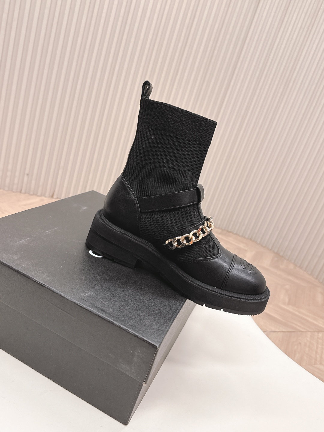 A pair of stylish black sock boots featuring gold chain hardware and chunky soles displayed on a white surface. - Hình 3