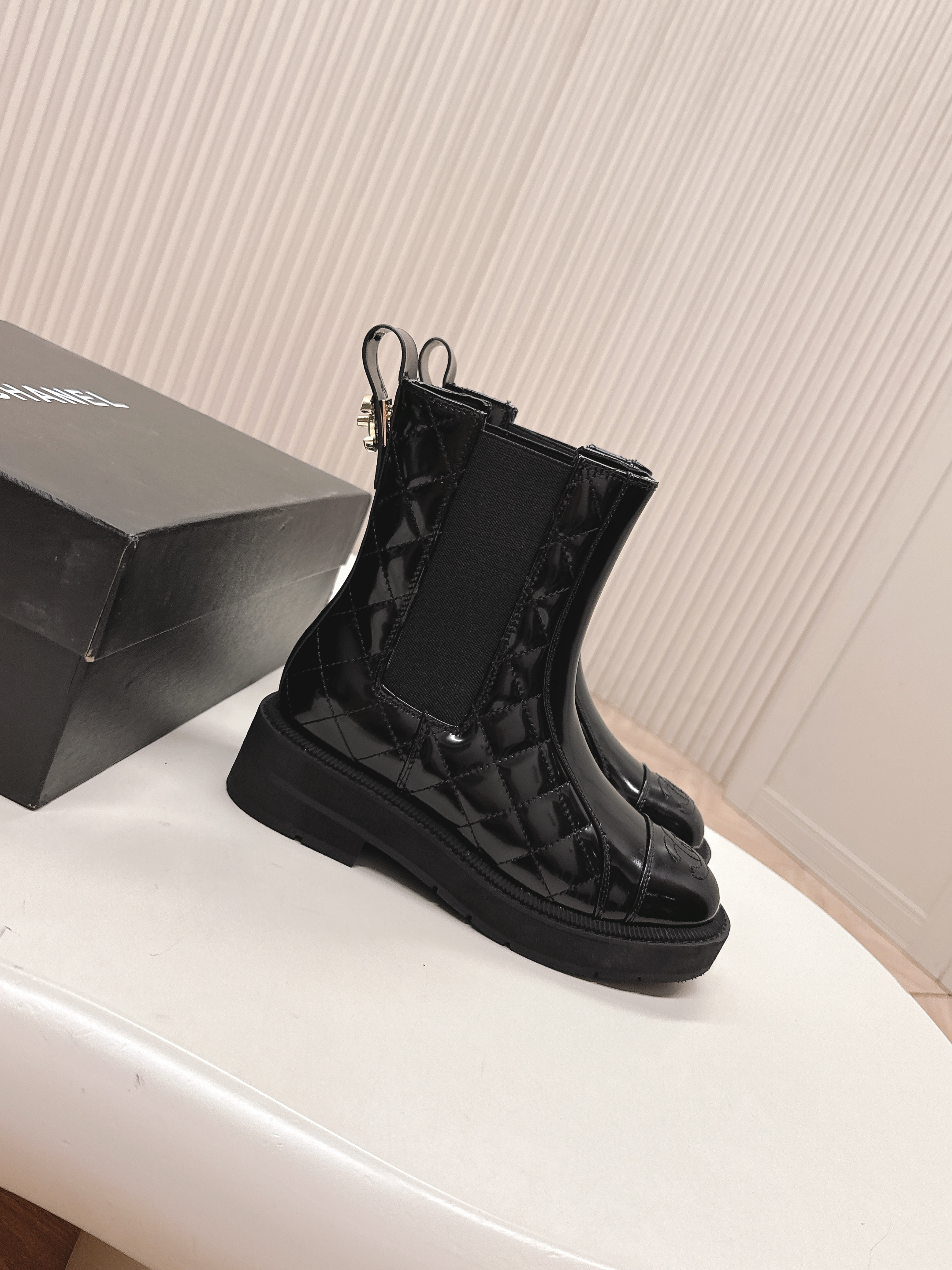 Pair of black Chanel quilted patent leather Chelsea boots with platform soles and embossed CC logo on the toe cap. - Hình 2