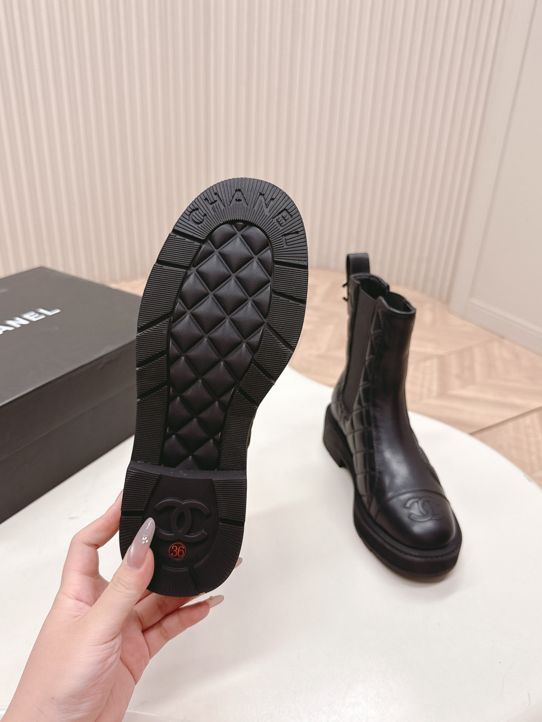 A pair of black quilted leather Chanel Chelsea boots with embossed CC logo on the toe and a chunky rubber sole. - Hình 7