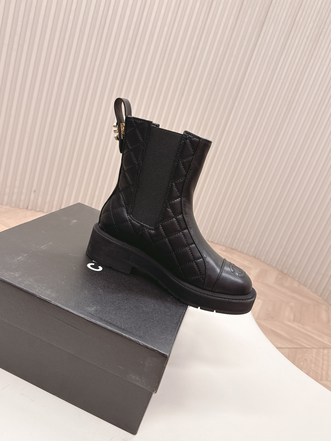 A pair of black quilted leather Chanel Chelsea boots with embossed CC logo on the toe and a chunky rubber sole. - Hình 6
