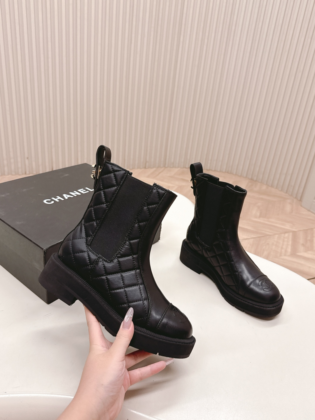 A pair of black quilted leather Chanel Chelsea boots with embossed CC logo on the toe and a chunky rubber sole. - Hình 4