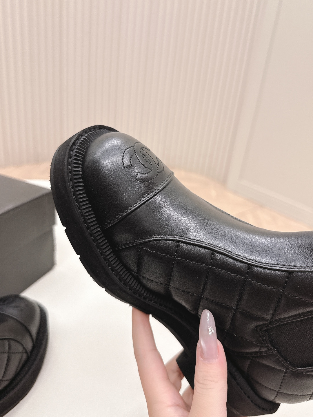 A pair of black quilted leather Chanel Chelsea boots with embossed CC logo on the toe and a chunky rubber sole. - Hình 3