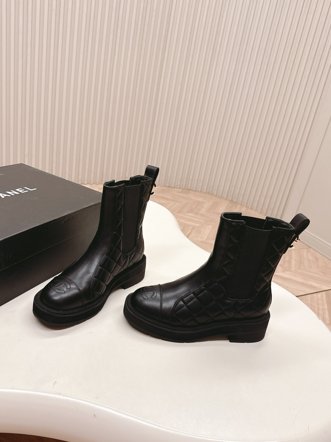 A pair of black quilted leather Chanel Chelsea boots with embossed CC logo on the toe and a chunky rubber sole. - Hình 2
