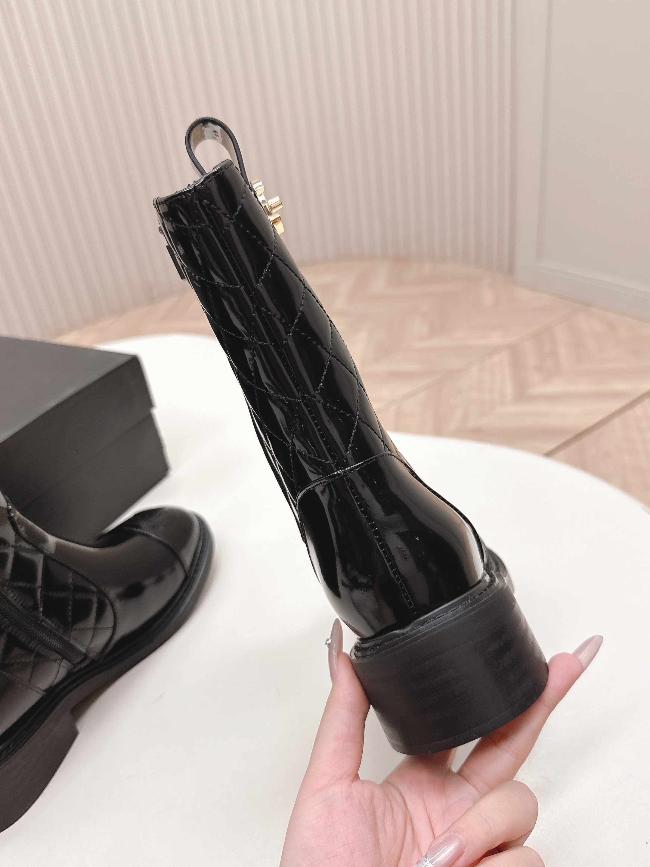 A pair of black Chanel quilted patent leather boots with gold CC logo and side zipper on a white surface. - Hình 8