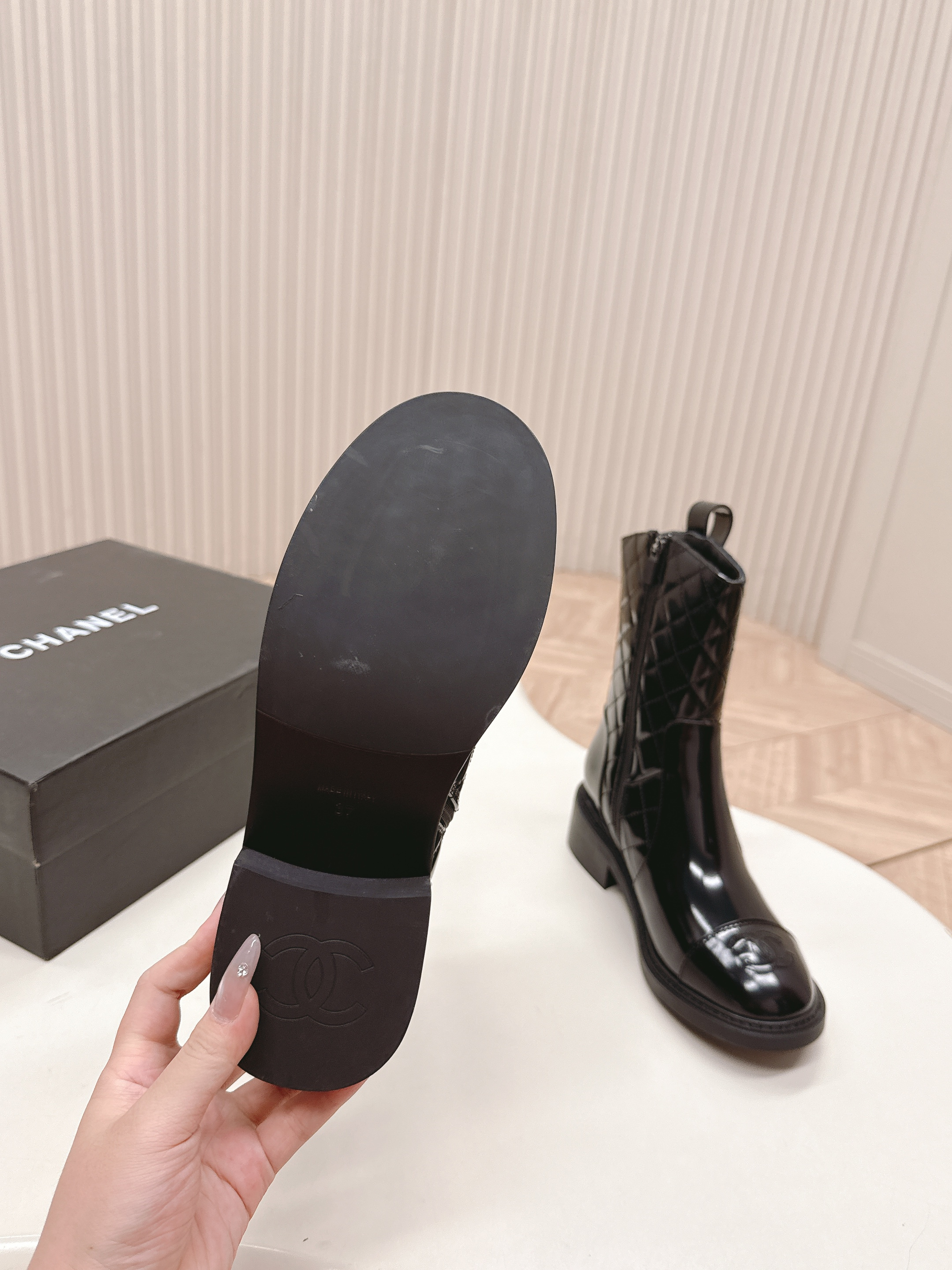 A pair of black Chanel quilted patent leather boots with gold CC logo and side zipper on a white surface. - Hình 7