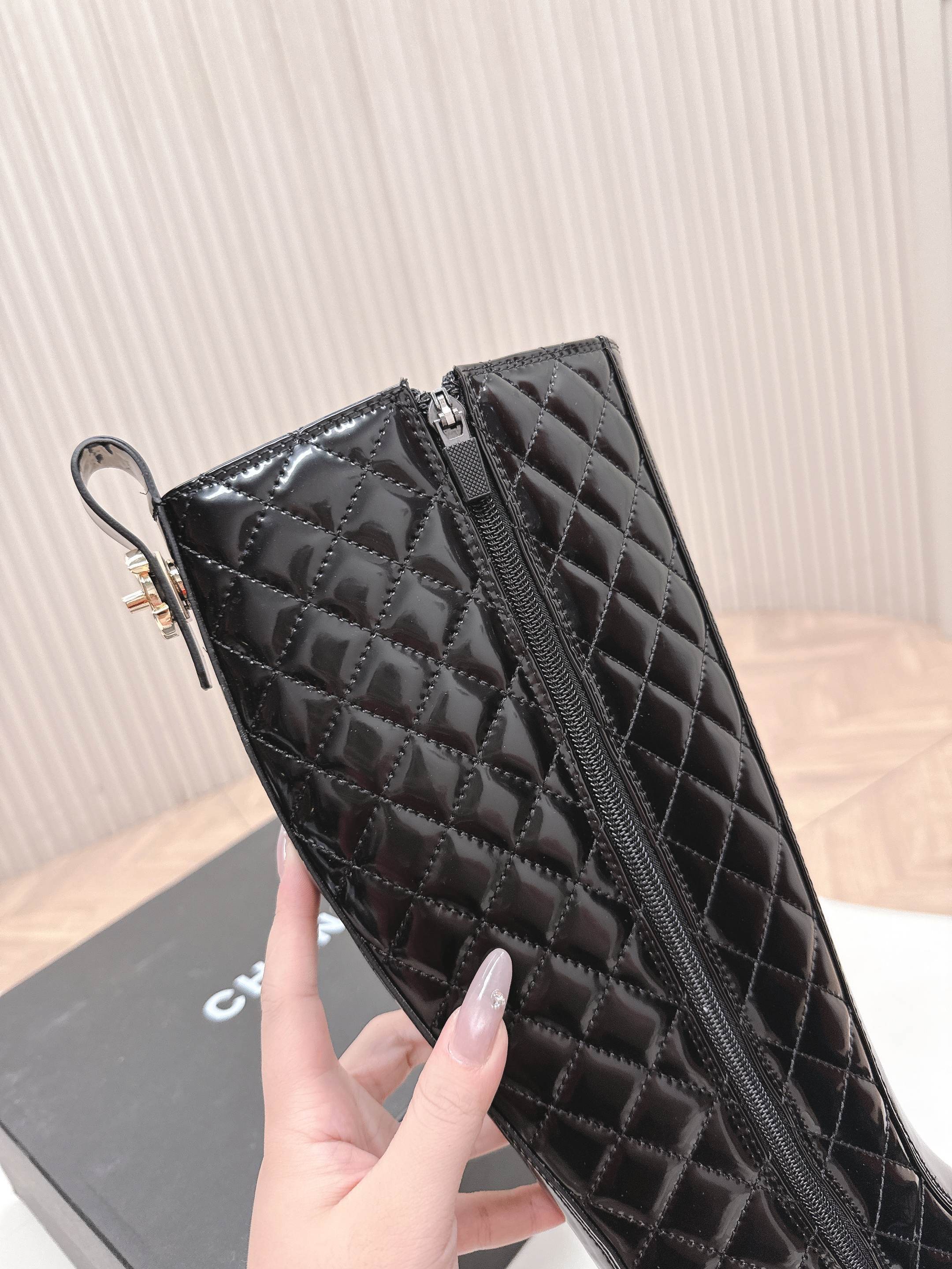 Pair of black Chanel quilted patent leather knee-high boots with CC logo on toe and chunky soles next to a Chanel box - Hình 8