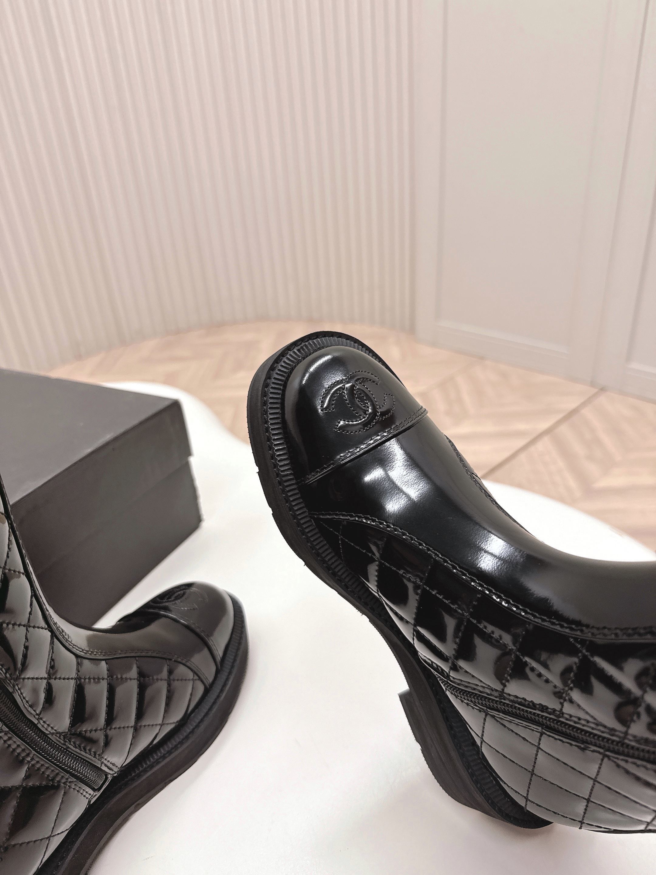 Pair of black Chanel quilted patent leather knee-high boots with CC logo on toe and chunky soles next to a Chanel box - Hình 5