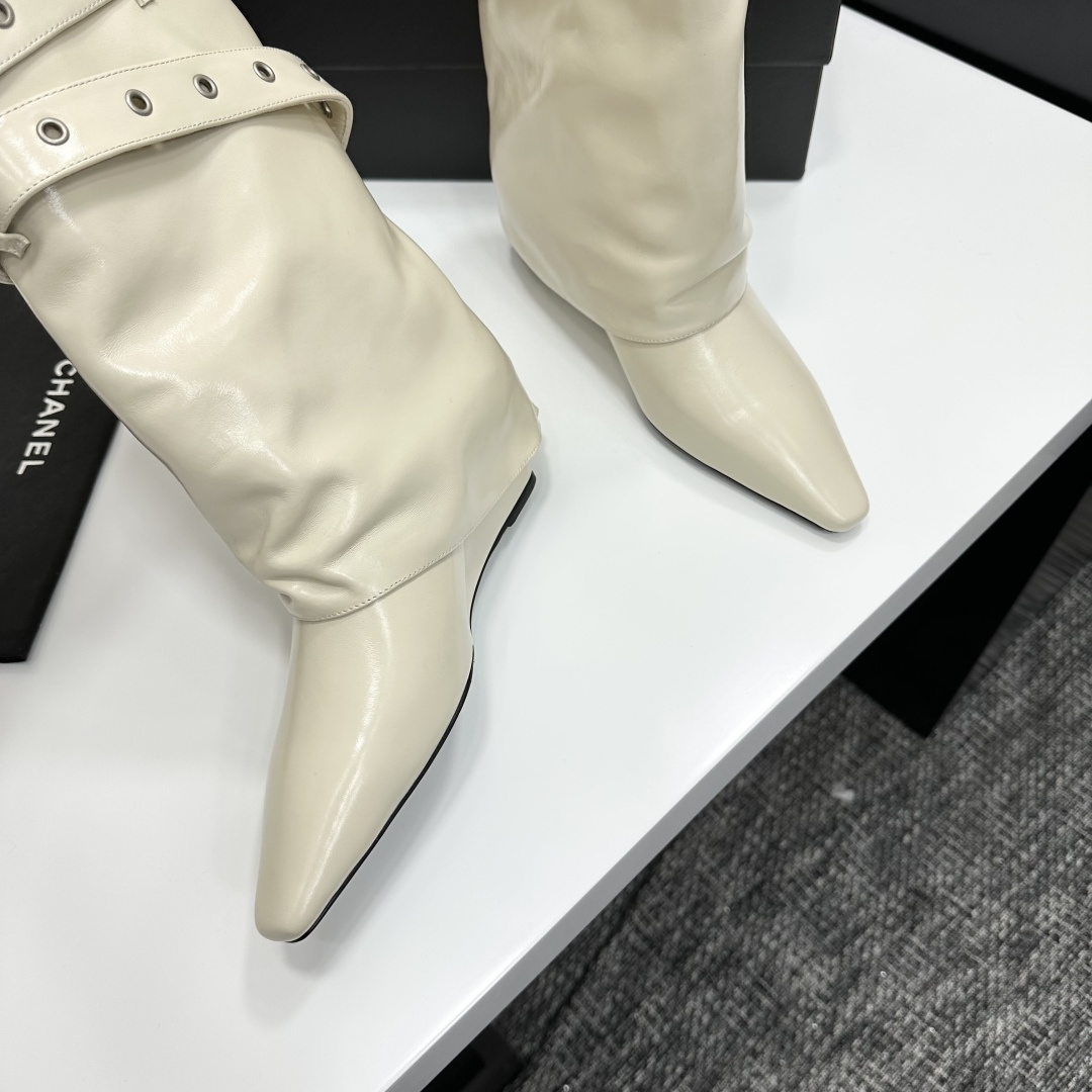 A pair of cream-colored slouchy leather wedge boots with pointed toes and double buckle strap details on a black display box. - Hình 8