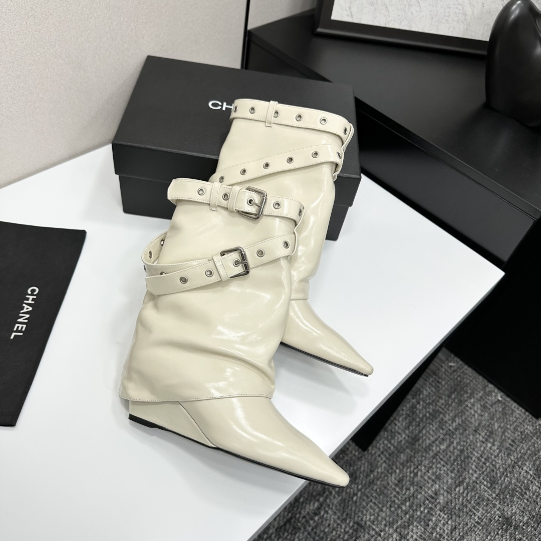 A pair of cream-colored slouchy leather wedge boots with pointed toes and double buckle strap details on a black display box. - Hình 7
