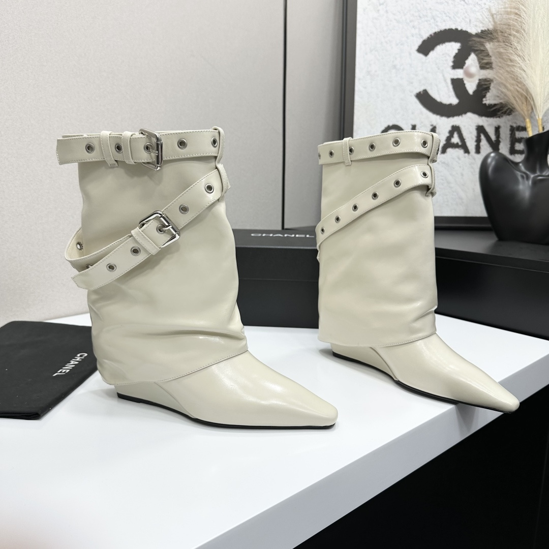A pair of cream-colored slouchy leather wedge boots with pointed toes and double buckle strap details on a black display box. - Hình 6