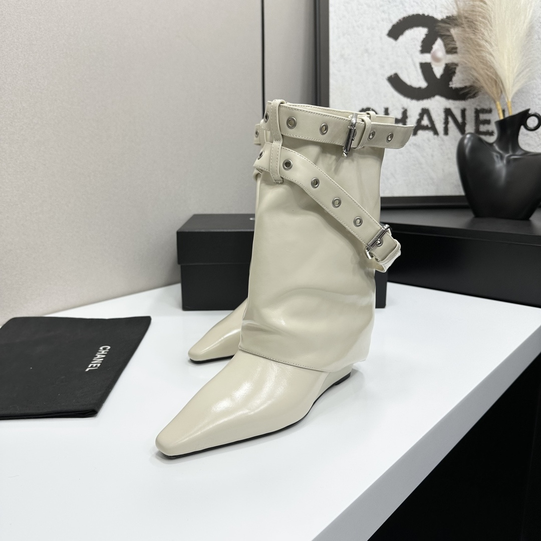 A pair of cream-colored slouchy leather wedge boots with pointed toes and double buckle strap details on a black display box. - Hình 4
